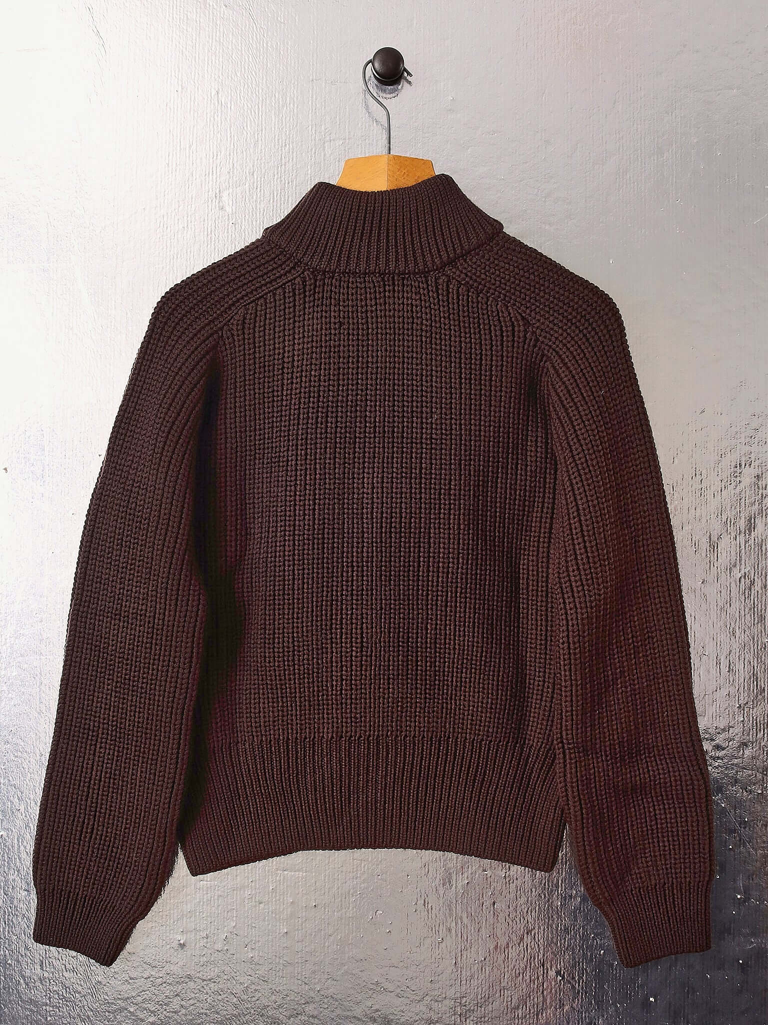A flat shot of the 'Circle' sweater on a hanger, showing the back of the garment and its sweater shape with long sleeves.