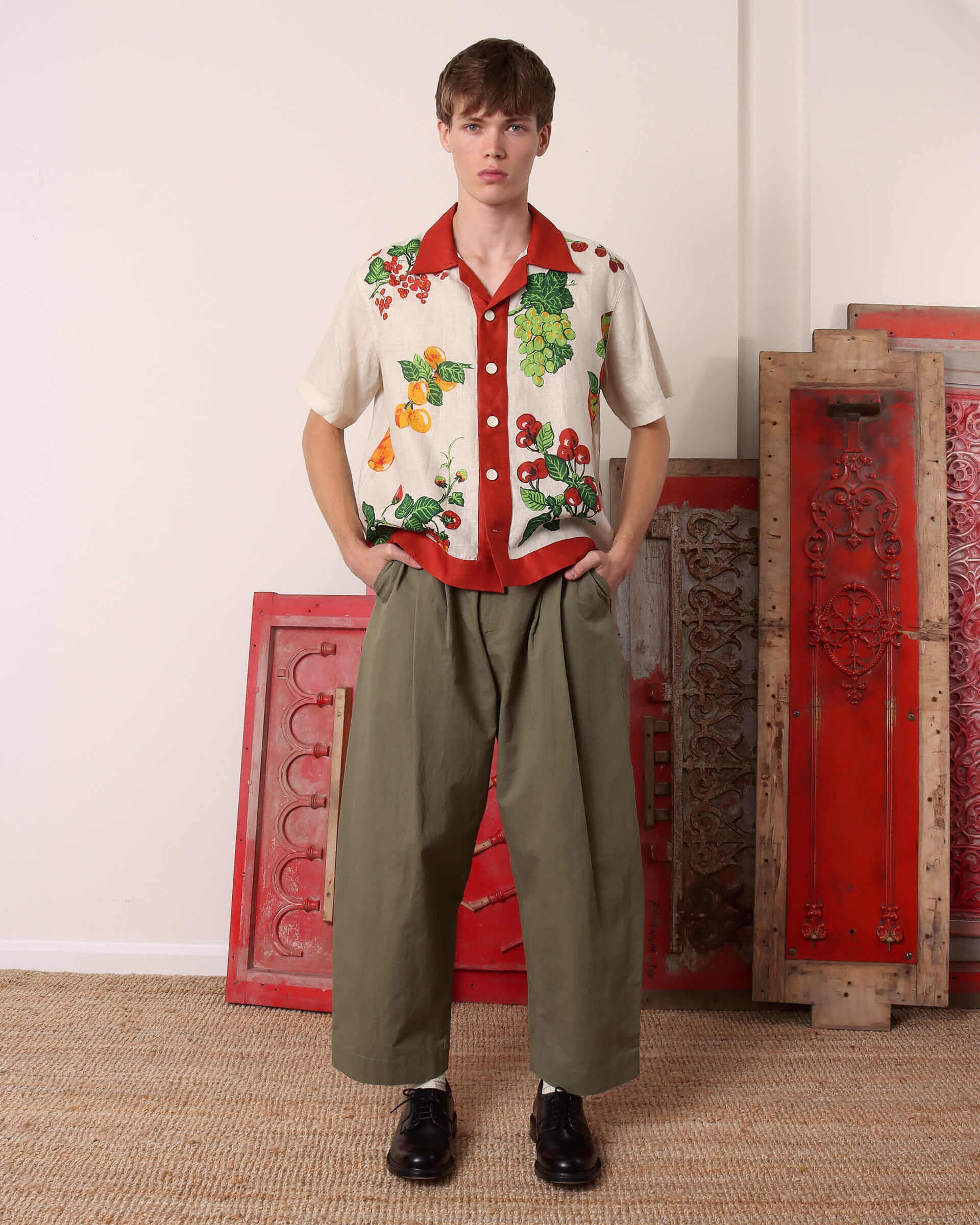 A model wears the 'Picnic' Shirt paired with the green 'Clarence' Trousers with his hands in the pockets.