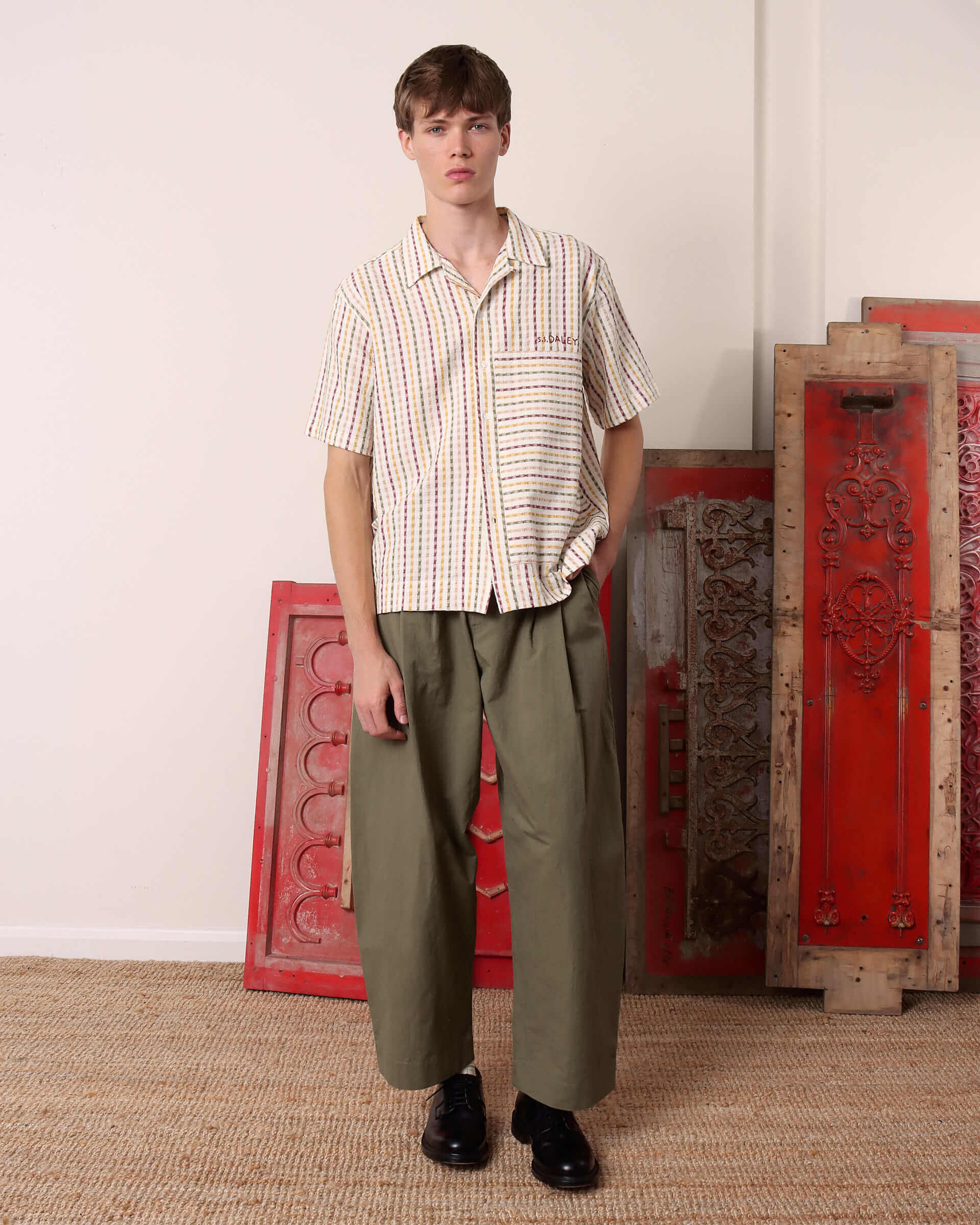 A model wears the 'Almer' Shirt in shirt sleeve with a pair of green trousers.