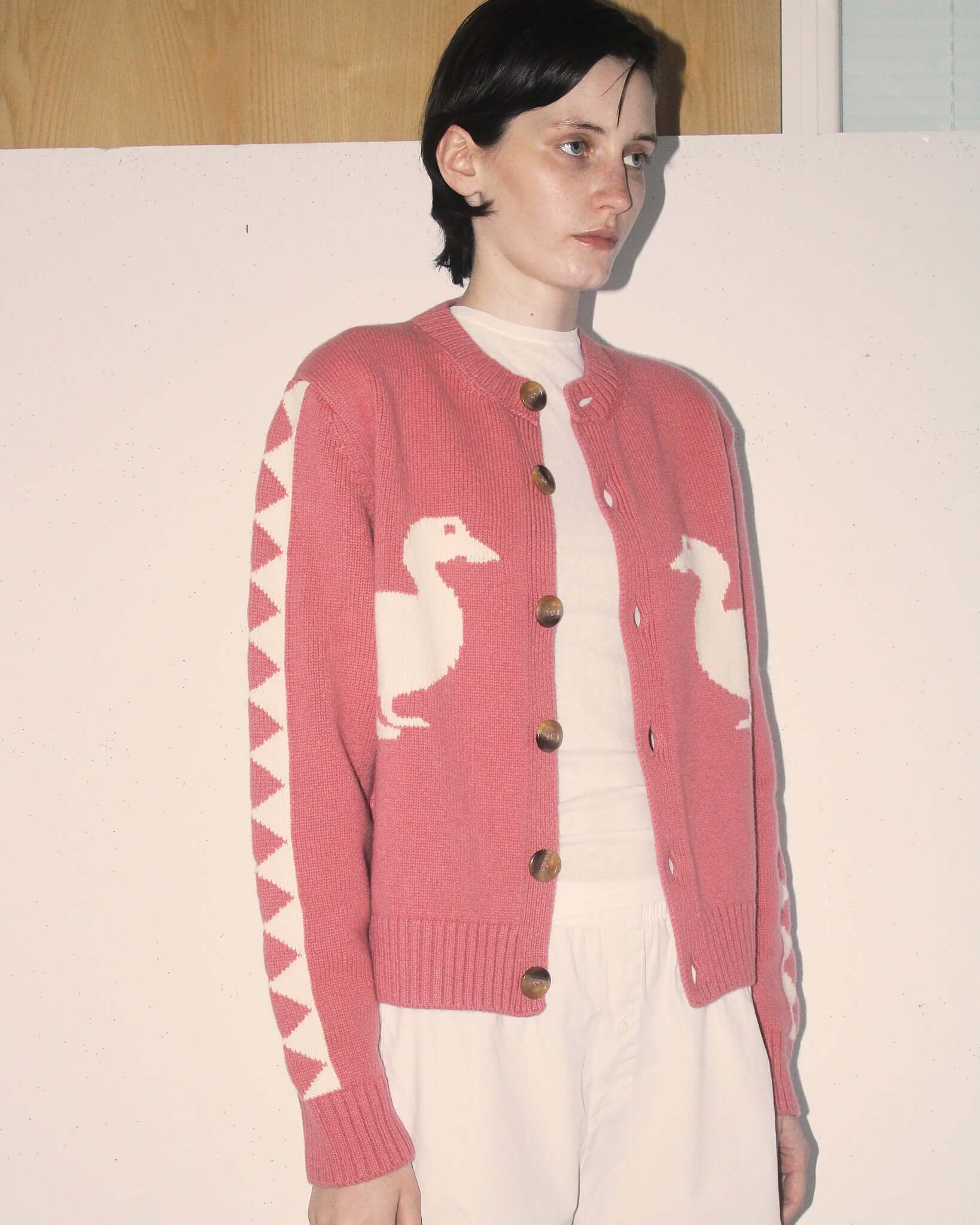 A detail shot of a model wearing the unbuttoned 'Jasper' Cardigan in pink.