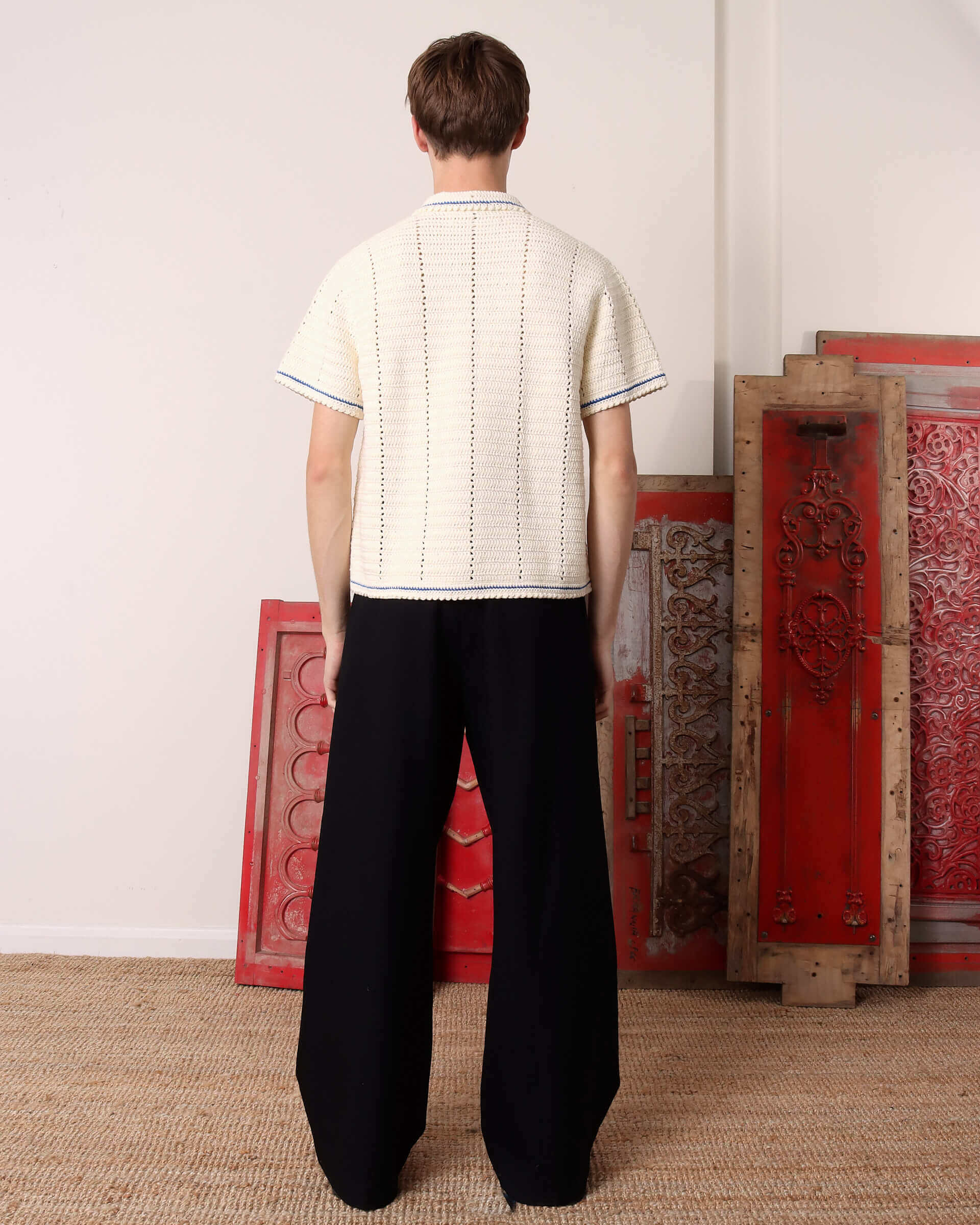 A model showing the back of the 'Abel' Crochet Shirt in cream and blue crochet.