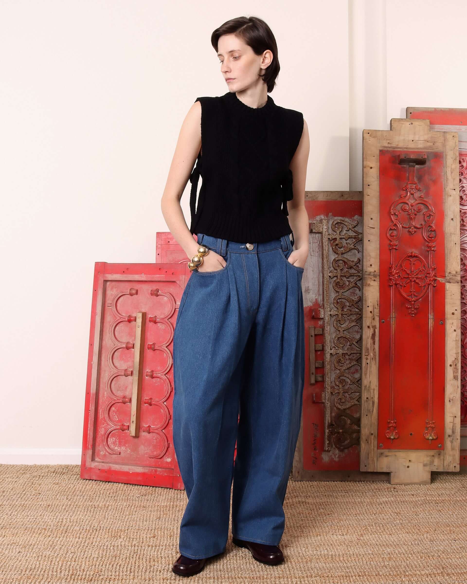 A model wears the black 'Blandine' Vest paired with a pair of blue denim trousers.