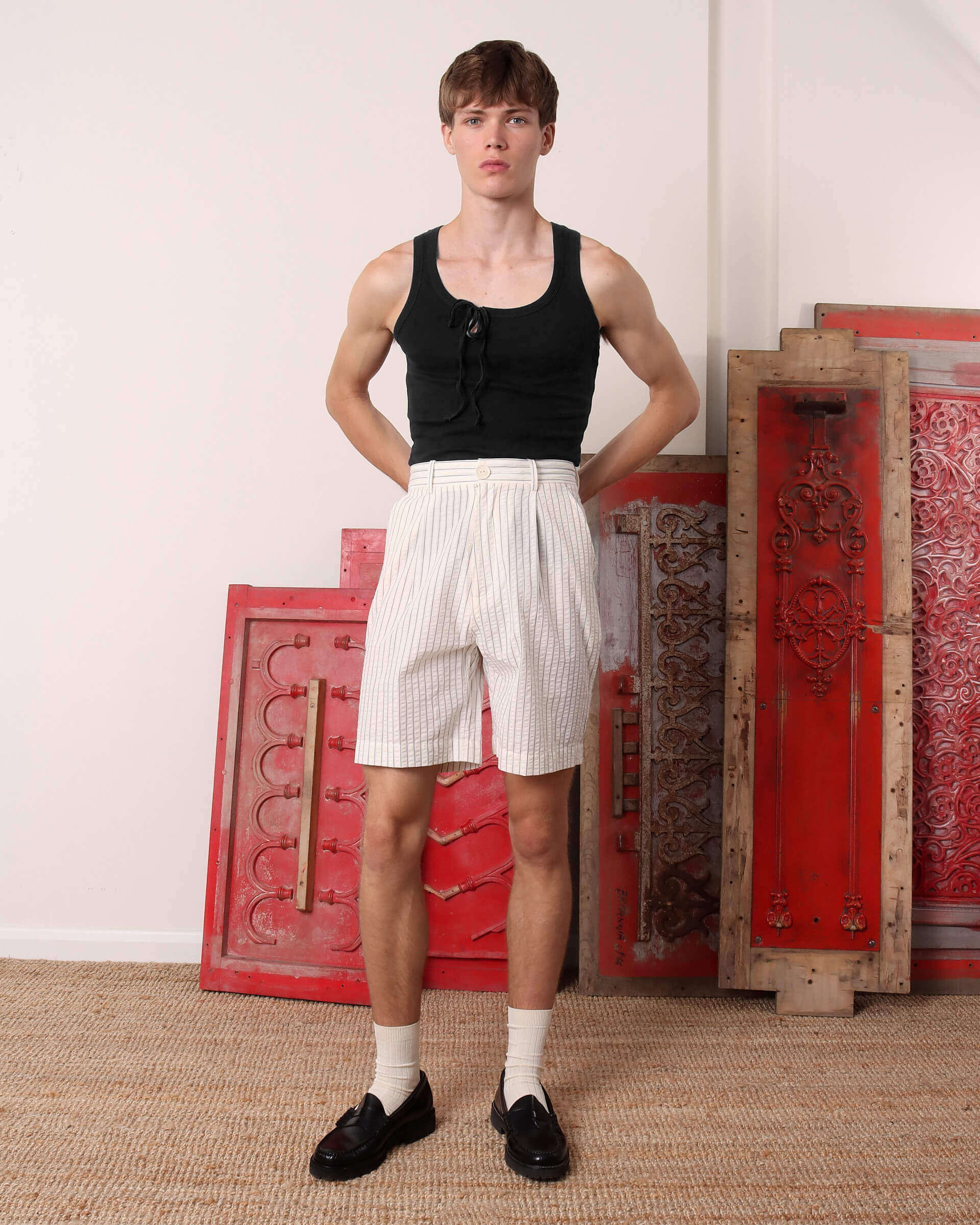 A model wears the 'Cochrane' Vest in black tucked into the 'Clement' seersucker mid-length shorts.