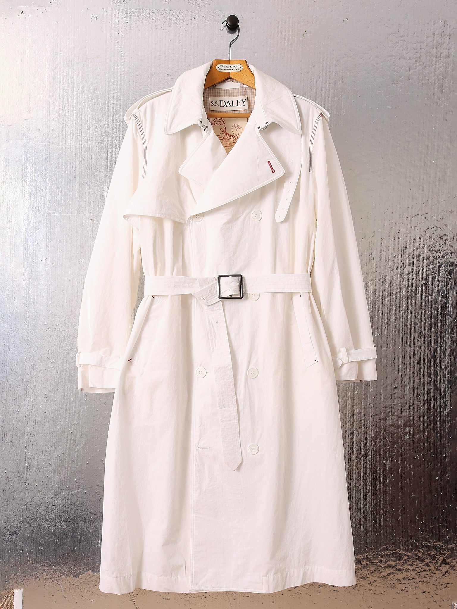 A flat shot of the 'Sophia' Trench in White, showing the white Japanese broadcloth fabric and contrasting red stitching.