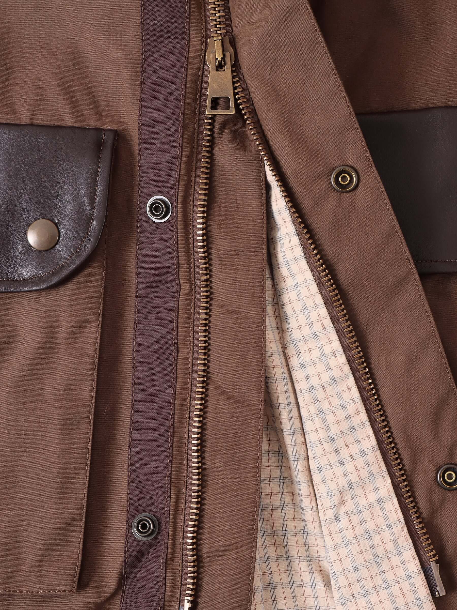 A detail shot of the Two-way front zip fastening, brass snap buttons, and check lining.