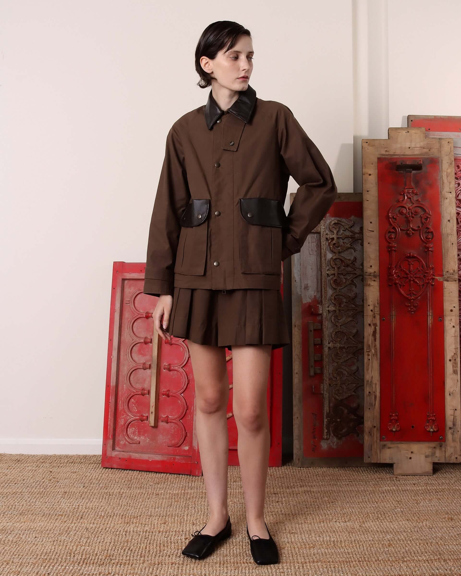 Model wears the 'Thea' Waxed Blouson Jacket buttoned up to the leather collar with matching pleated shirts. 