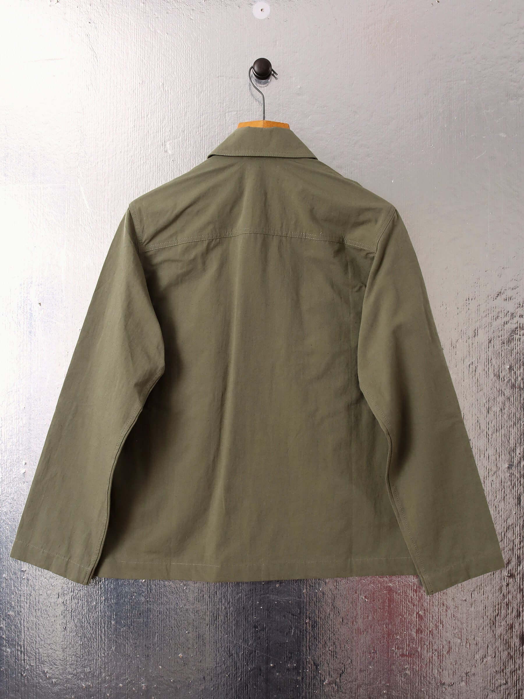 A flat shot of the 'Clarence' Chore Jacket in green showing the back of the garment.