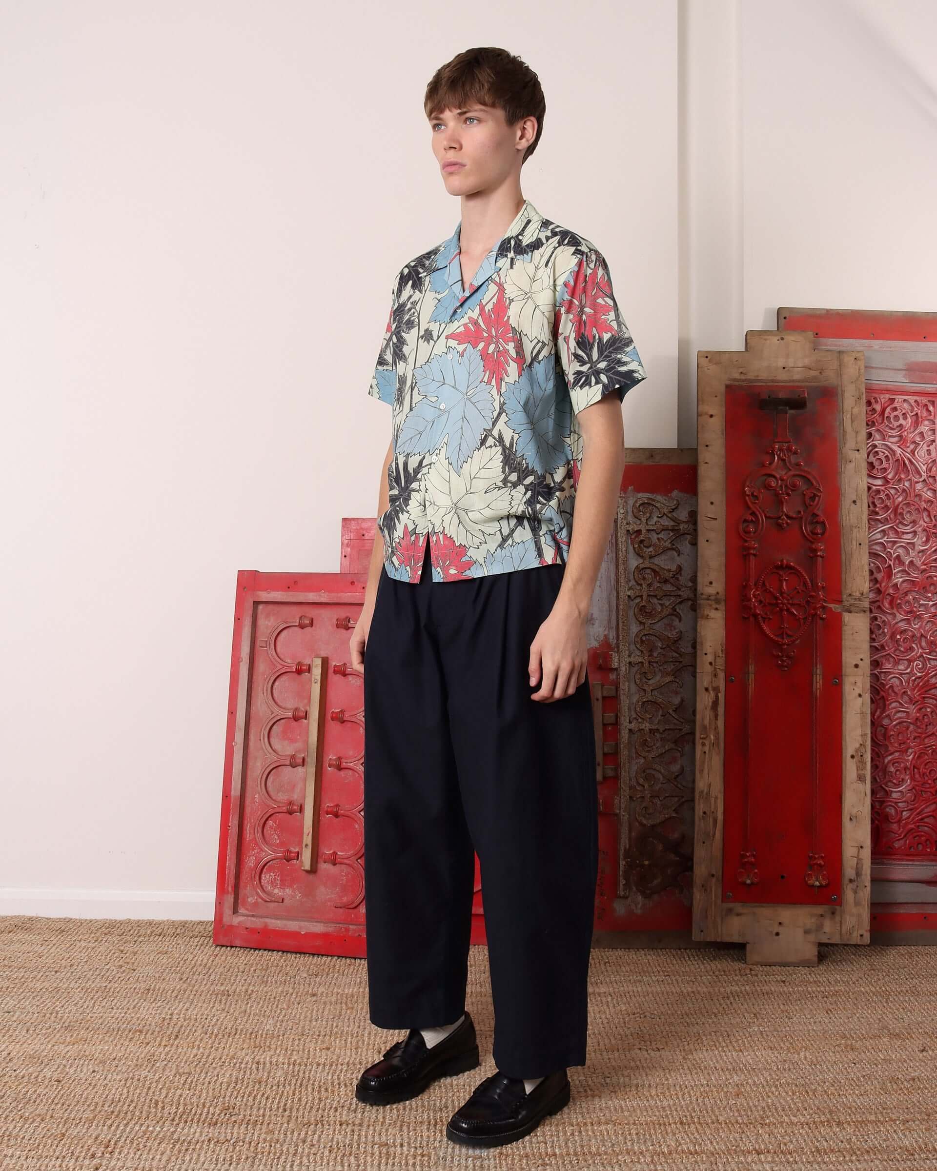 A model stands to the side wearing the 'Otis' Short Sleeve Shirt showing the boxy fit and relaxed linen fabric.