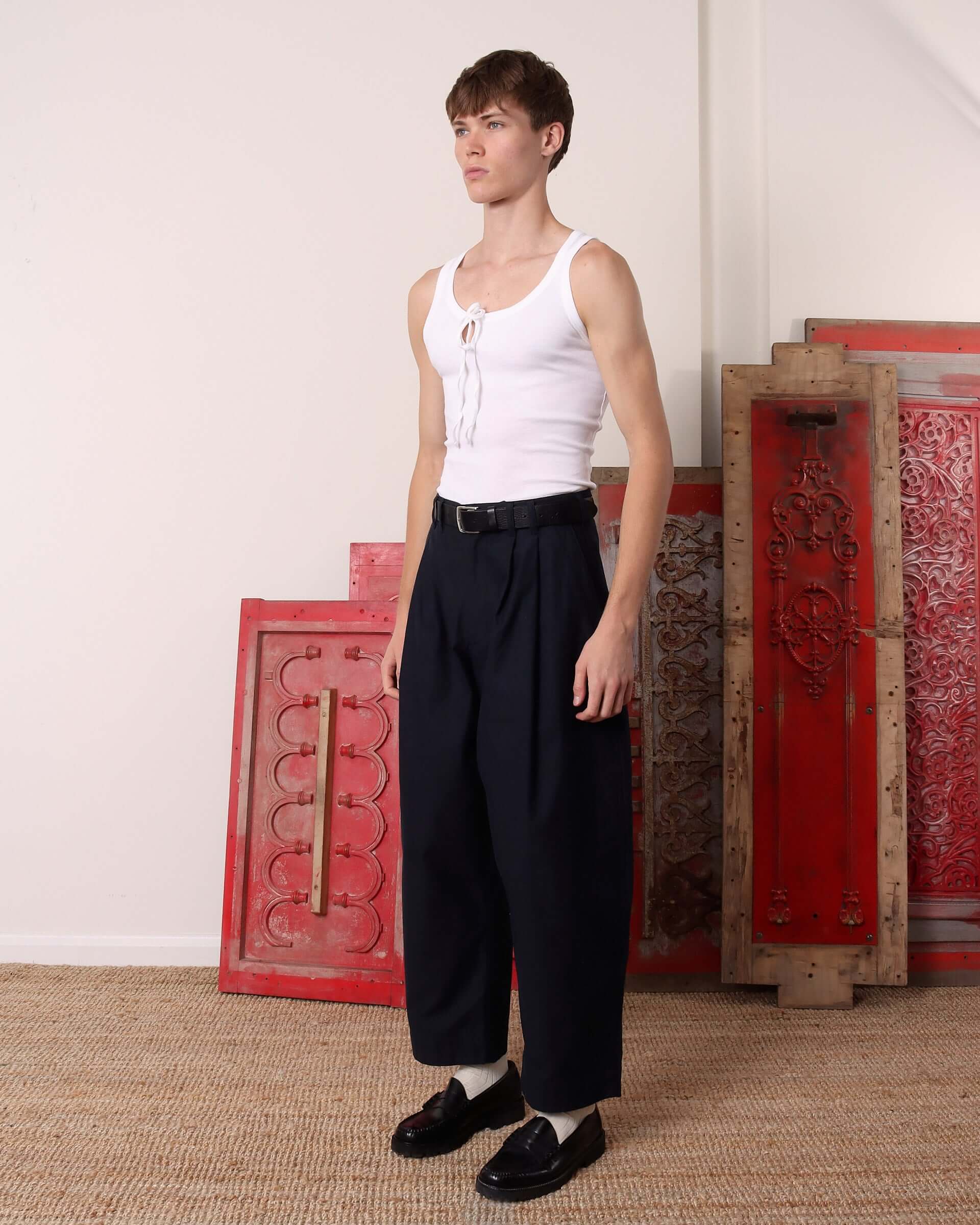 A model shows the side details and rounded leg shape of the navy 'Clarence' Trousers.