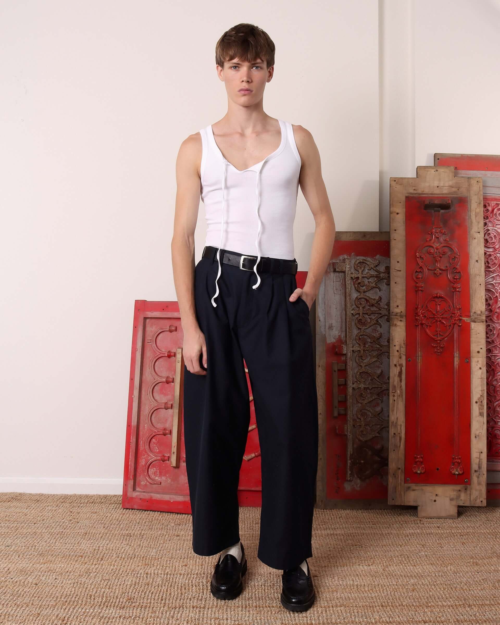 Model wearing a white 'Cochrane' vest paired with the 'Clarence' trousers in navy.
