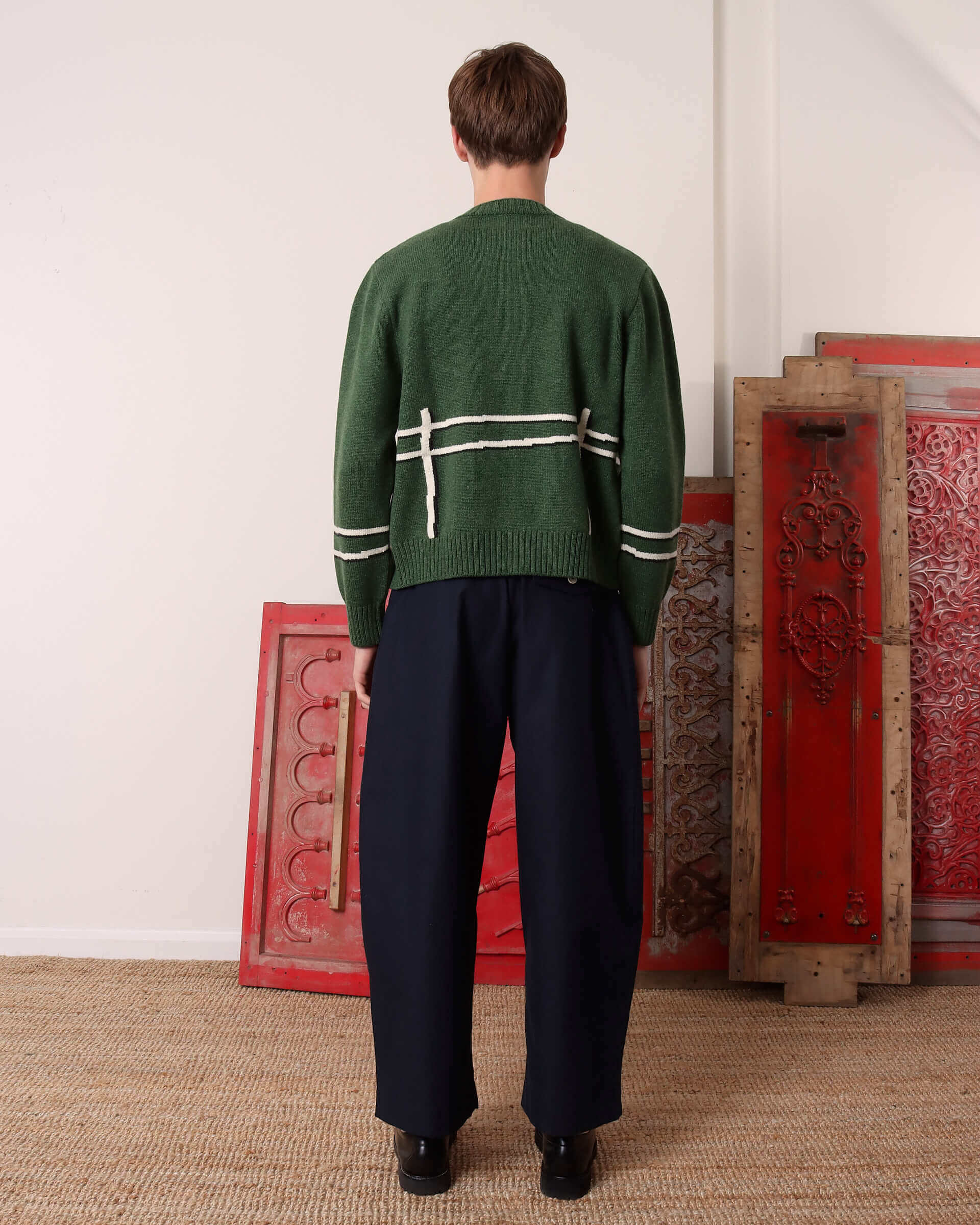 A model shows the back of the 'Cyril' Lamb Motif Cardigan in green.