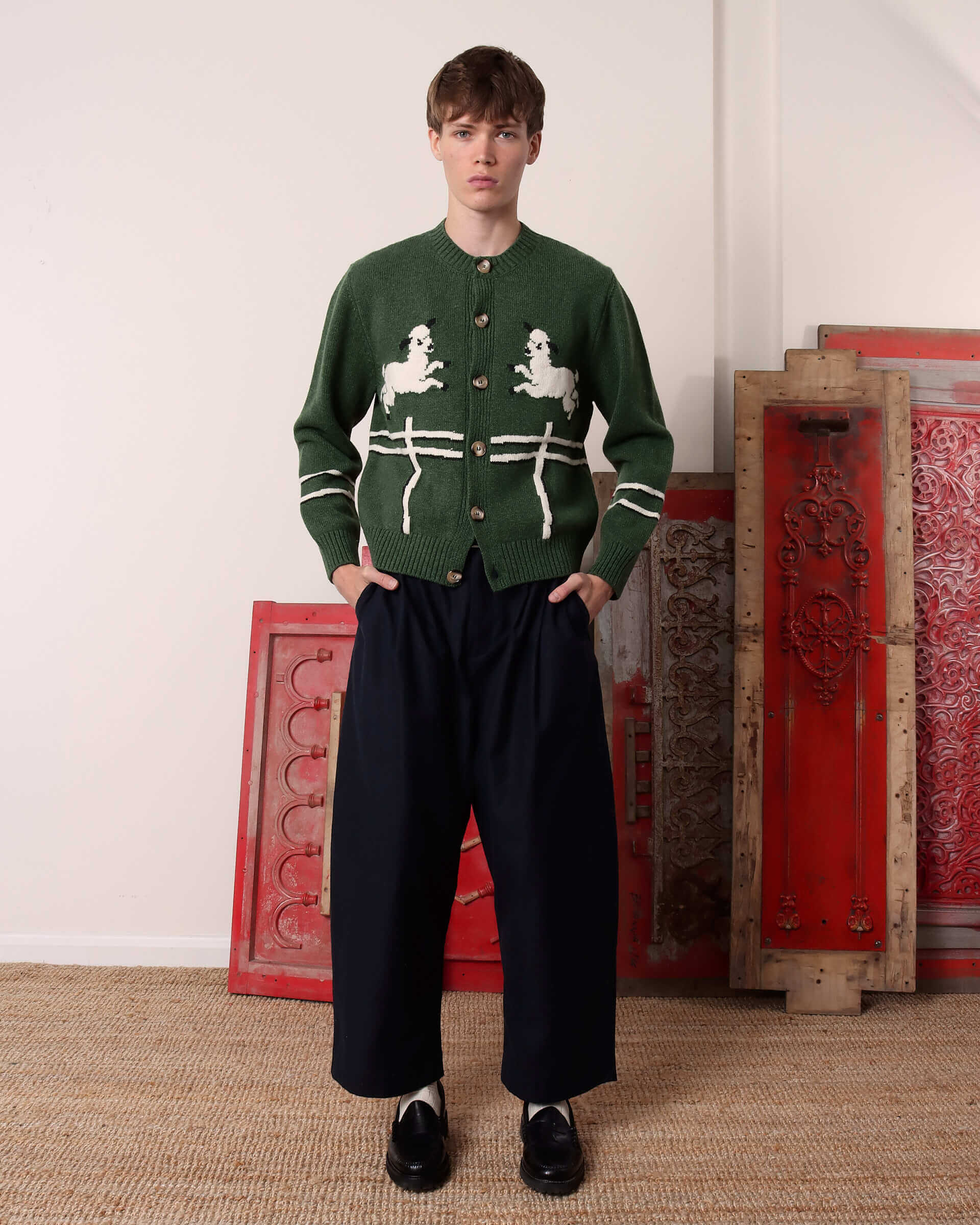 A model wears the 'Cyril' Lamb Motif Cardigan in green buttoned up.