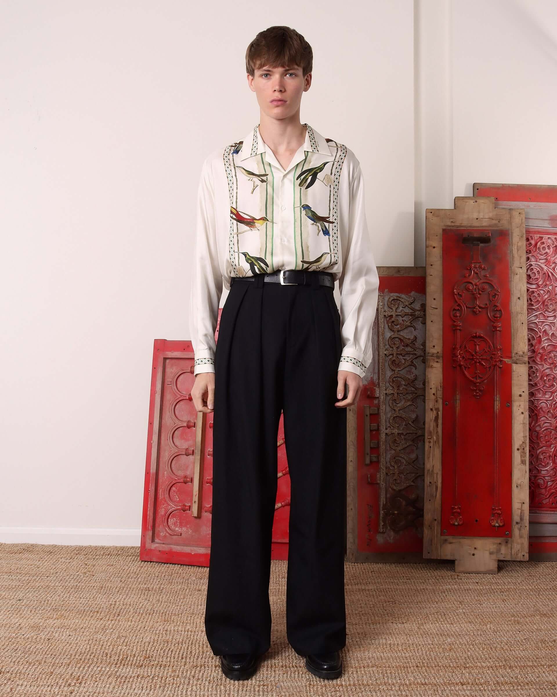 A model wears the long sleeve 'Birdwatcher' Shirt tucked into the black 'George' Trousers complete with a black belt.