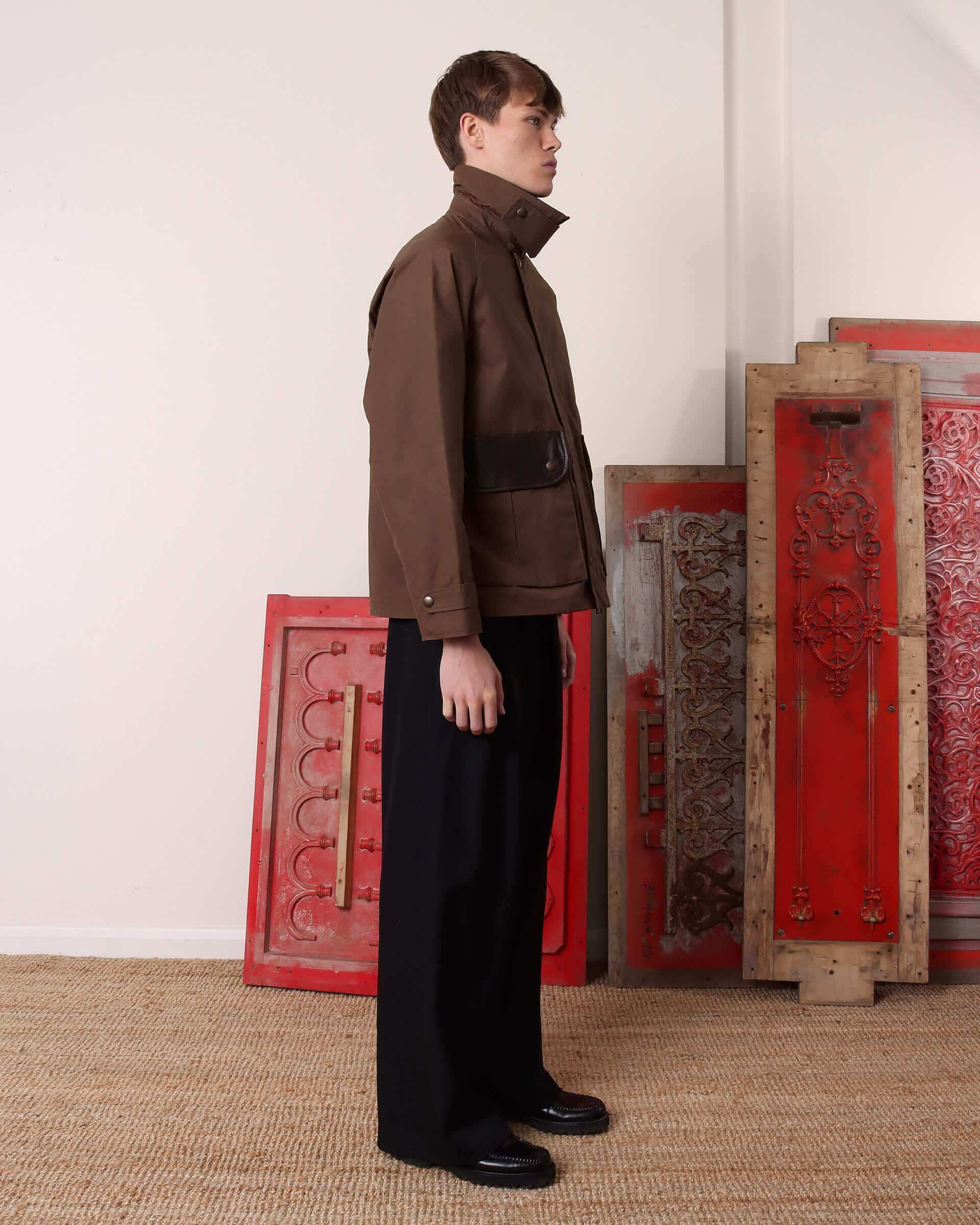 A model shows the side of the 'Theodore' Waxed Blouson with the collar up and throat-latch fastened. 
