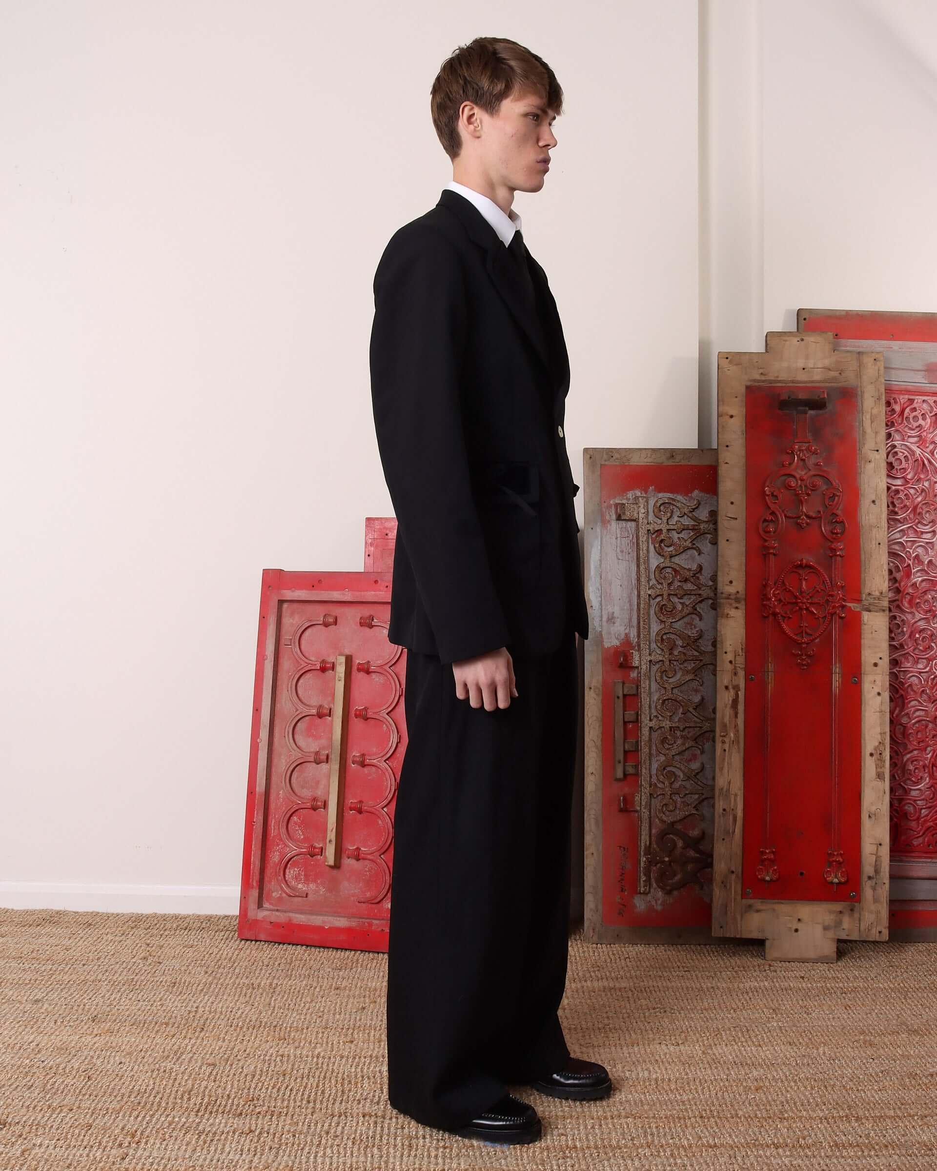 A model shows the side of the black 'George' Single Breasted Suit Jacket and trousers.