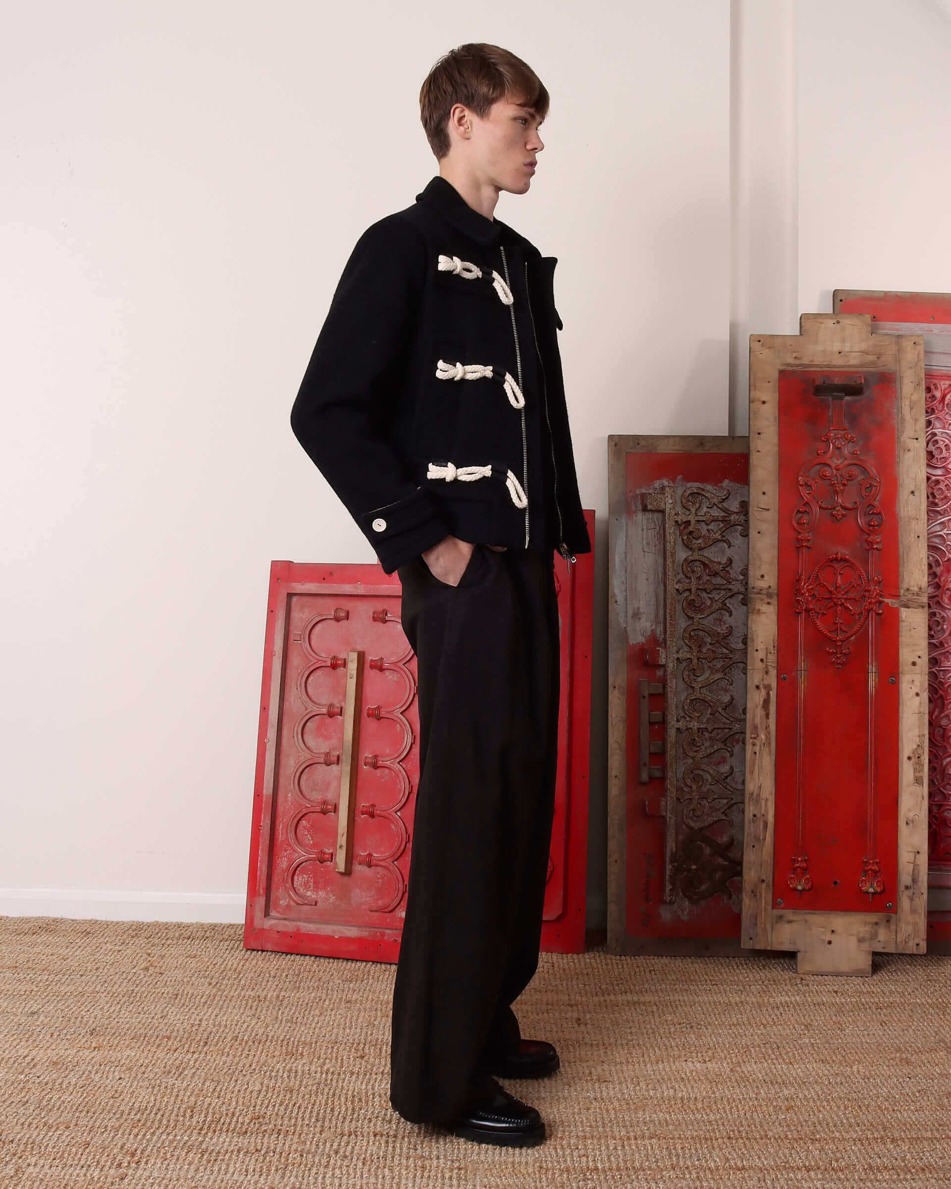 A model shows the 'Alwyn' Duffle Jacket from the side, showing the folded cuff detail and white button fastening on the sleeve.
