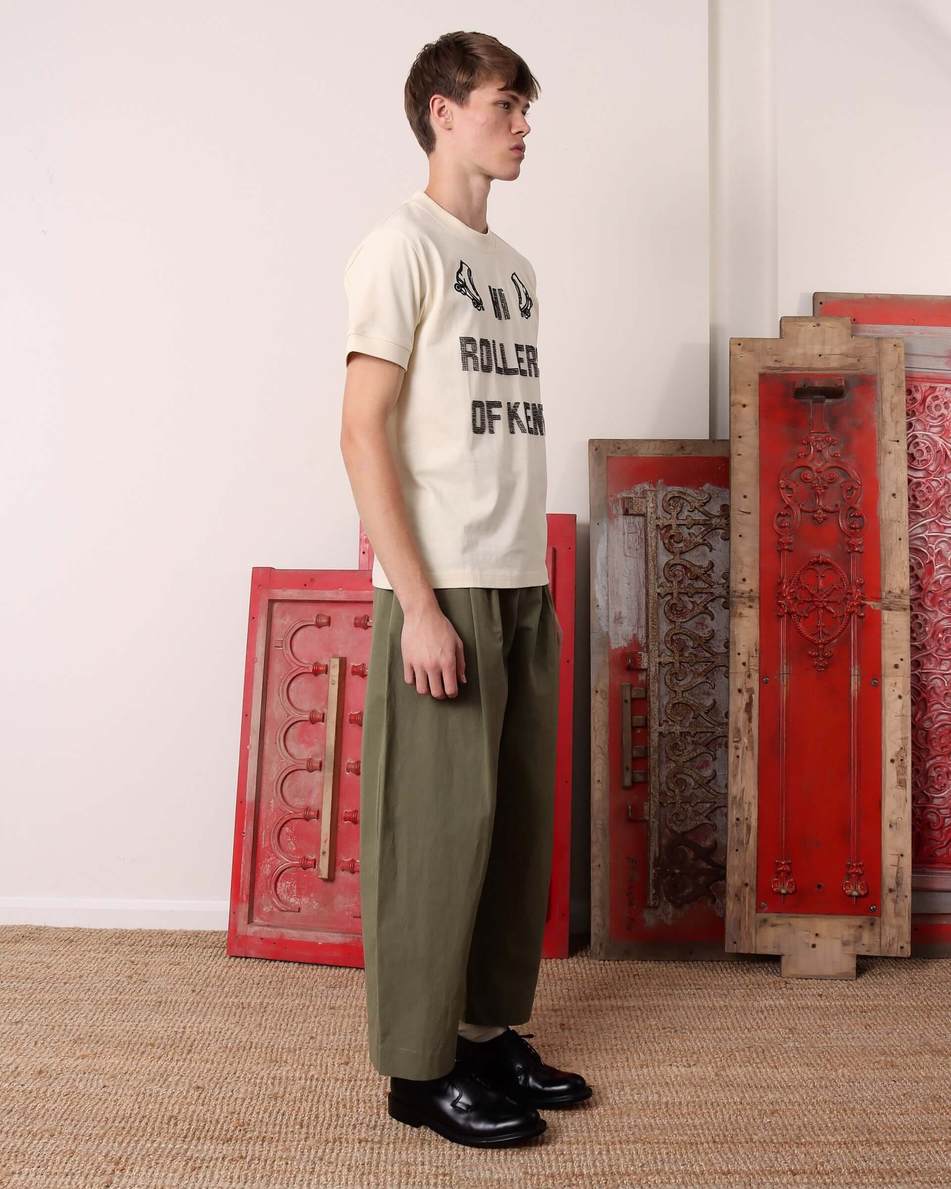 A model shows the side of the 'Hi Rollers' T-Shirt in ecru.