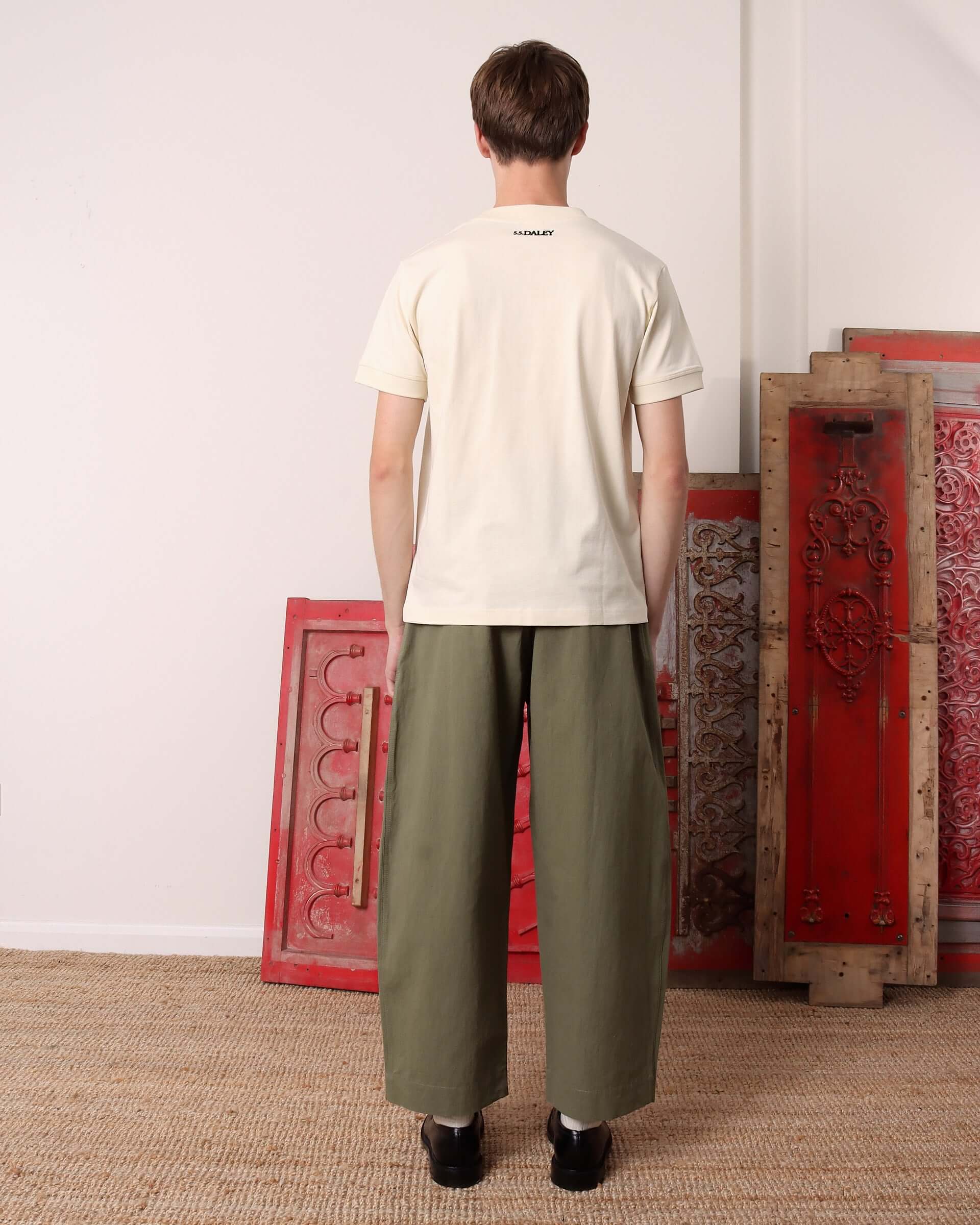 A model shows the back of the ecru 'Hi Rollers' T-Shirt in ecru and the small black S.S.DALEY logo detail.