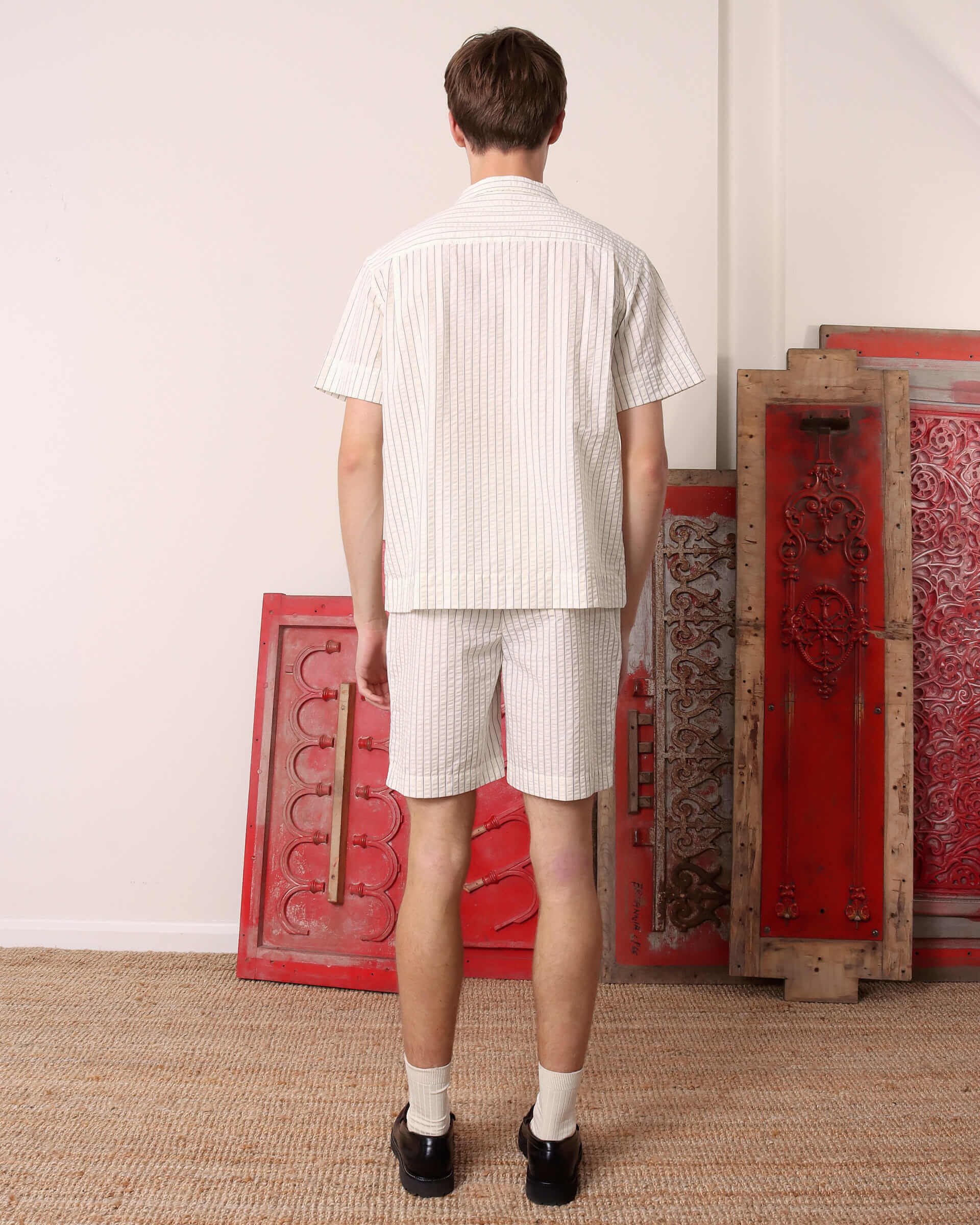 A model shows the back of the 'Turning' Shirt in seersucker and the matching 'Clement' Seersucker Shorts.