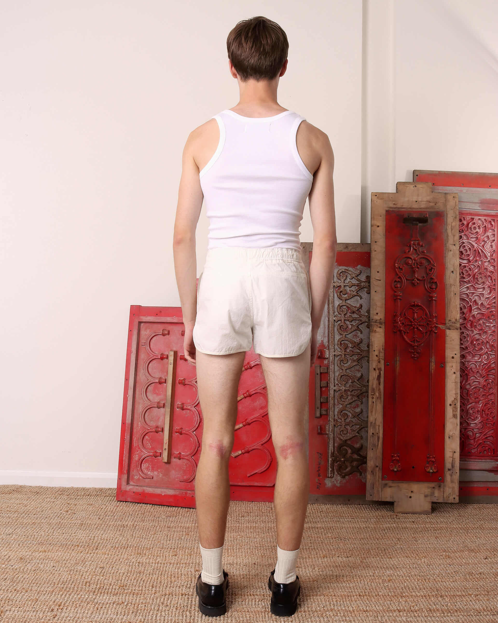 A model shows the back of the 'Cochrane' Vest in white and white shorts.