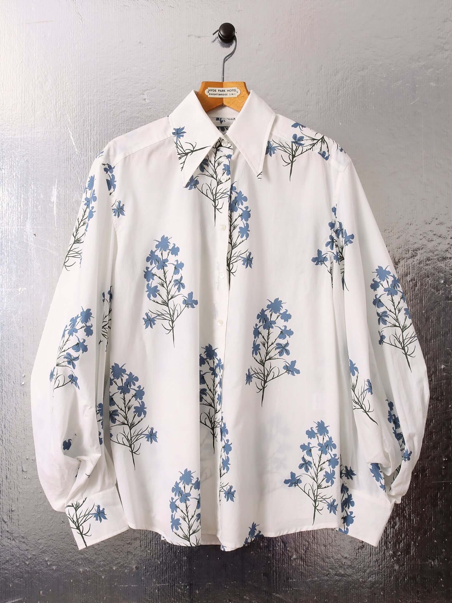 A flat shot of the 'Clem' Long Sleeve Shirt buttoned to the collar showing the front and the blue delphinium print inspired by a 1970s British Botany Guide on a white base.