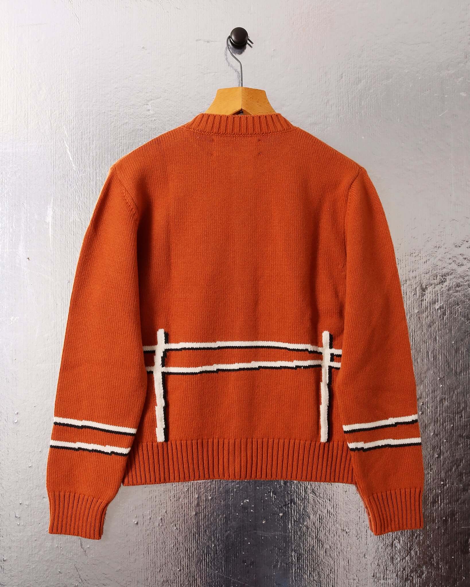 A flat shot shows the back of the 'Cyril' Lamb Cardigan in tawny and the white fence motif across the back and bottom of each sleeve.