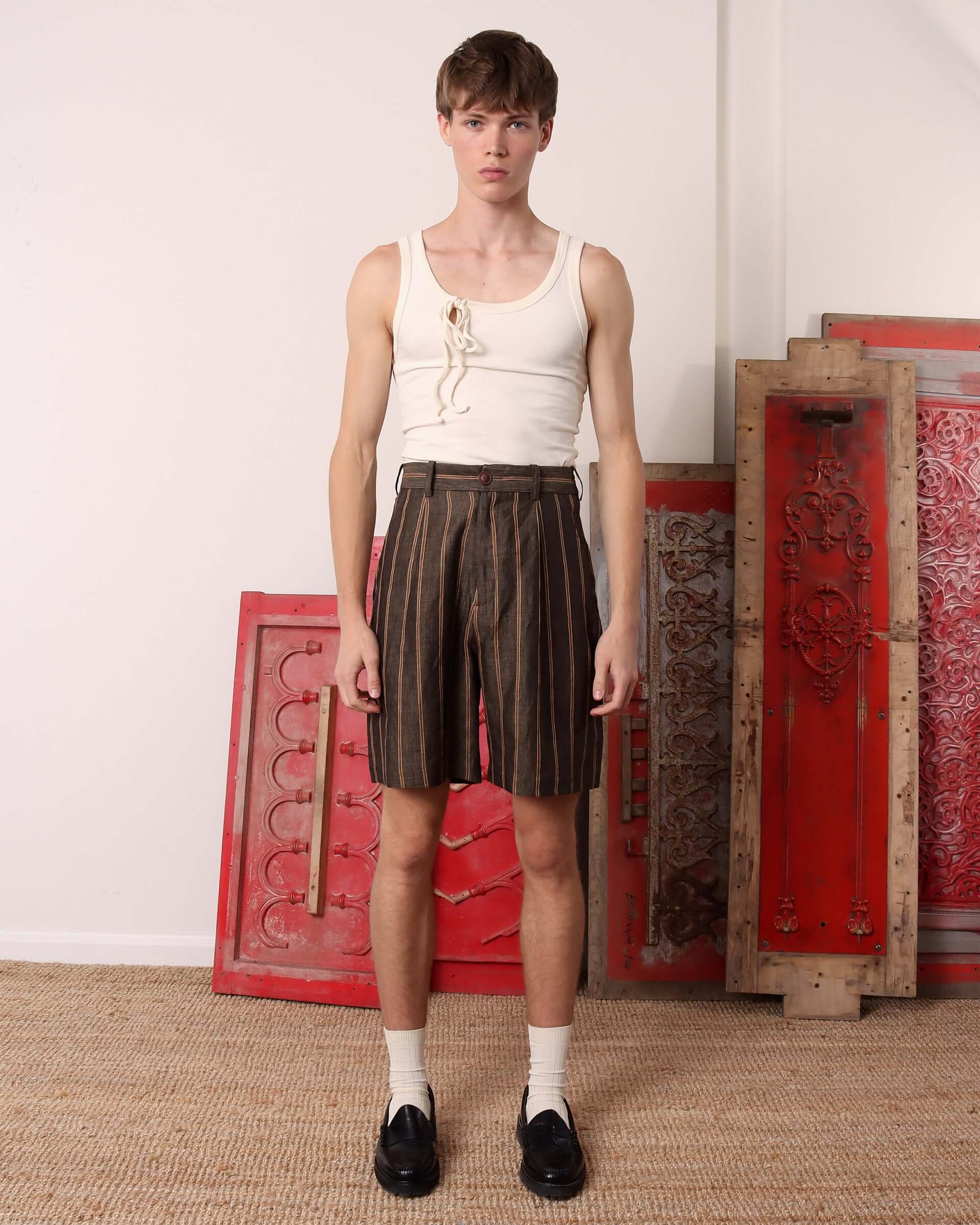 Model wearing the 'Rafferty' Pleated Suit Shorts in brown with beige stripes. 