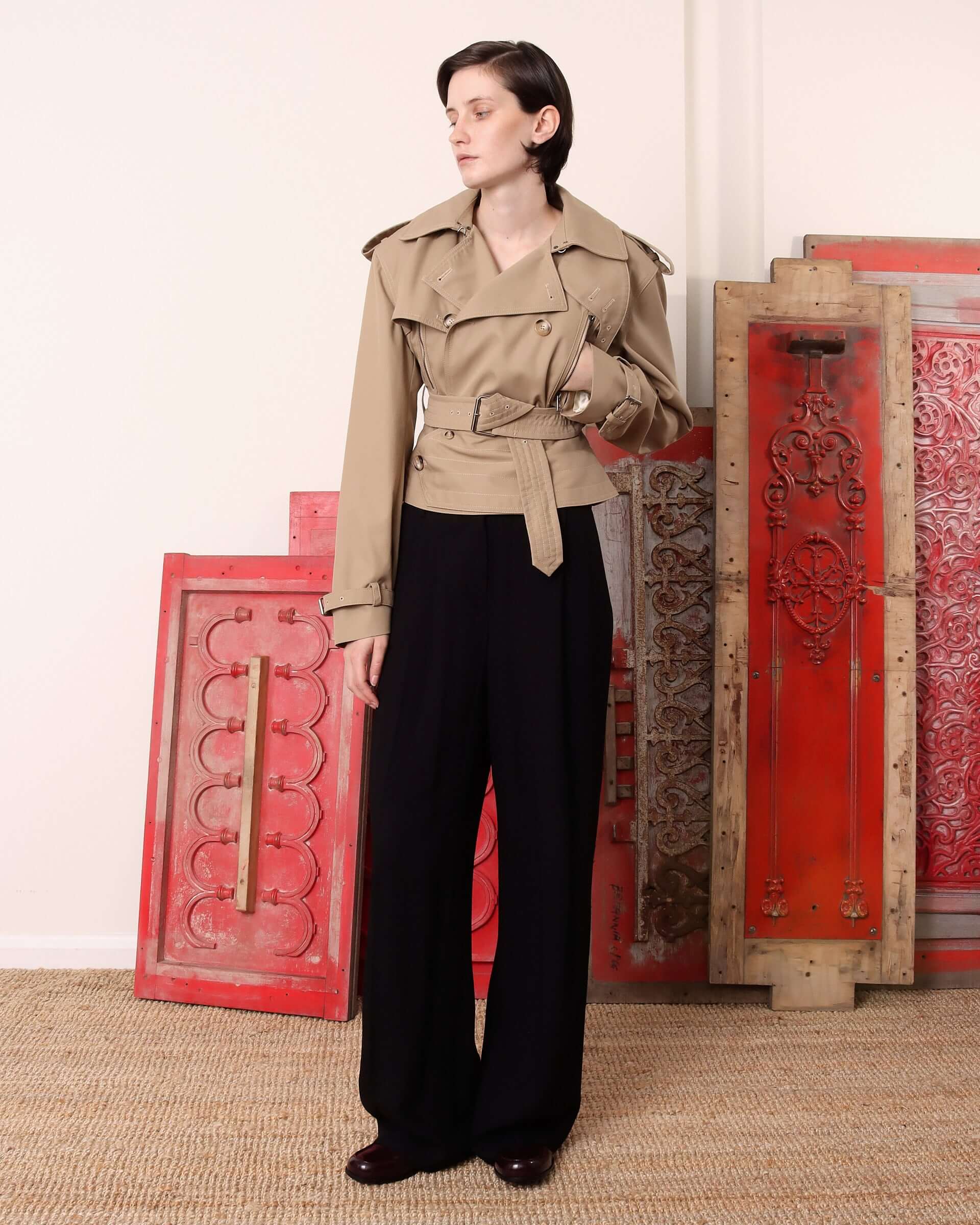 A model wears the 'Eliza' Peplum Trench buttoned up without the adjustable buckled neck closure fastened, showing the slight v-neckline. 