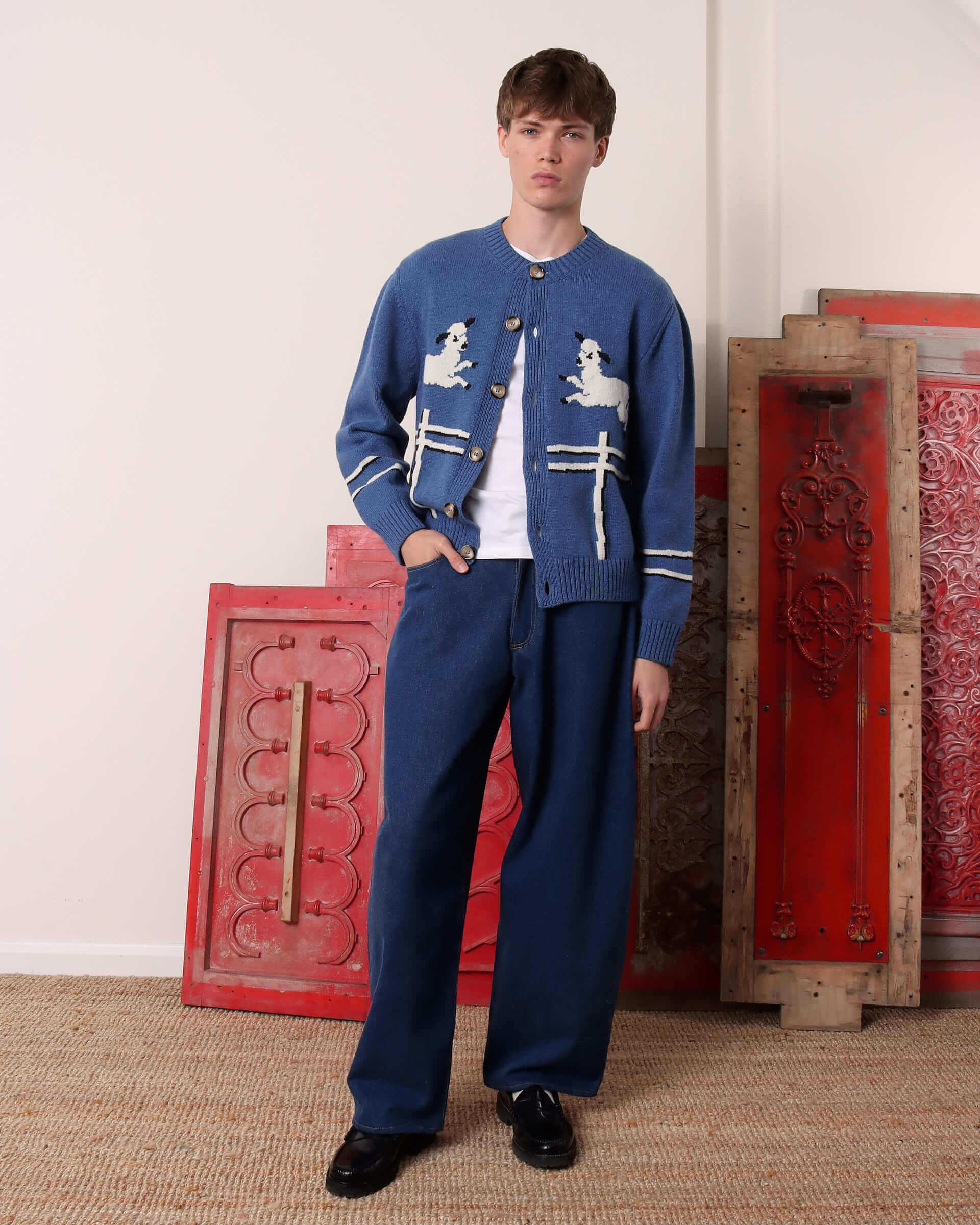 A model wears the 'Cyril' Lamb Motif Cardigan in blue with matching blue denim.