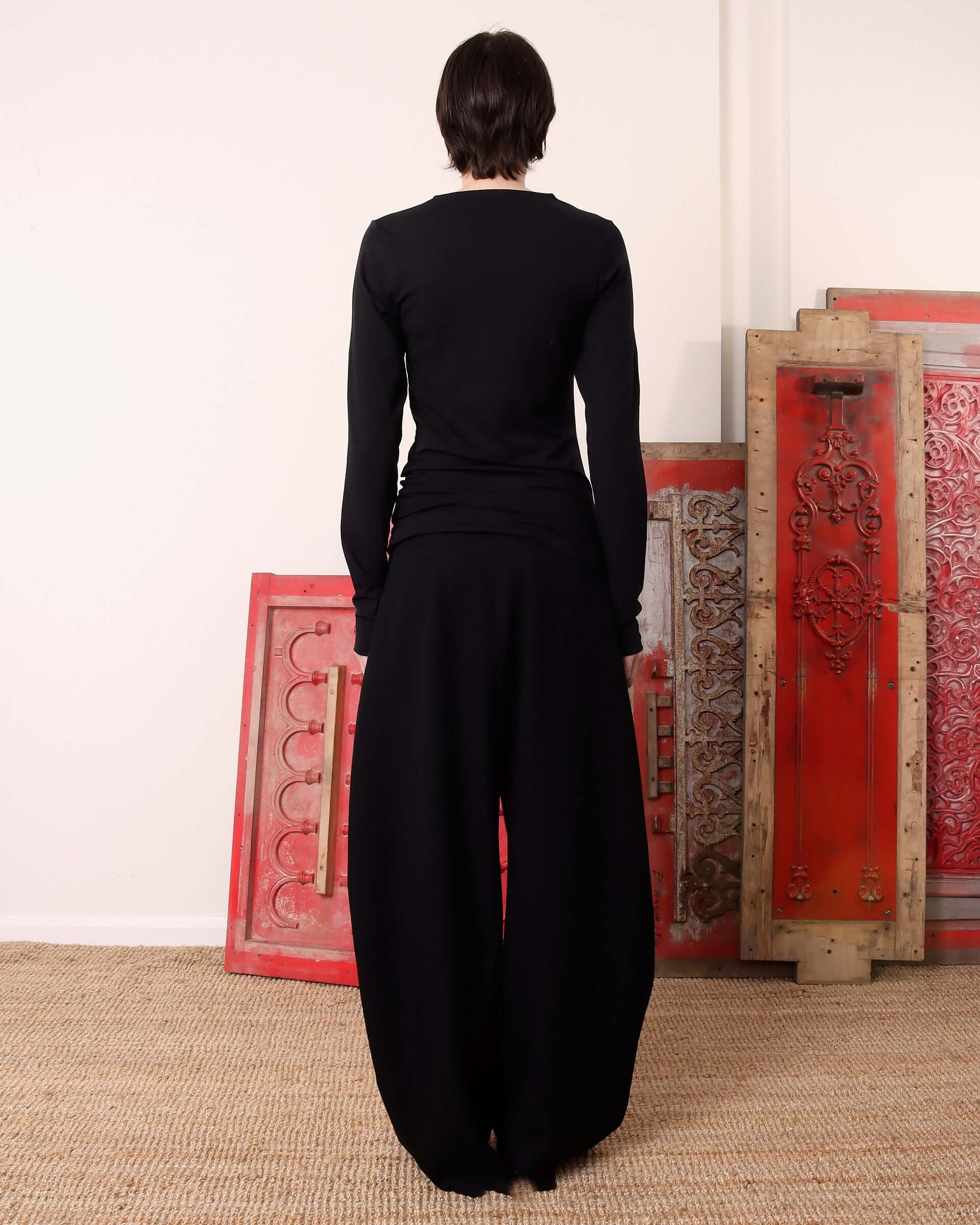 A model shows the back of the black, long sleeve 'Aker' Henley.