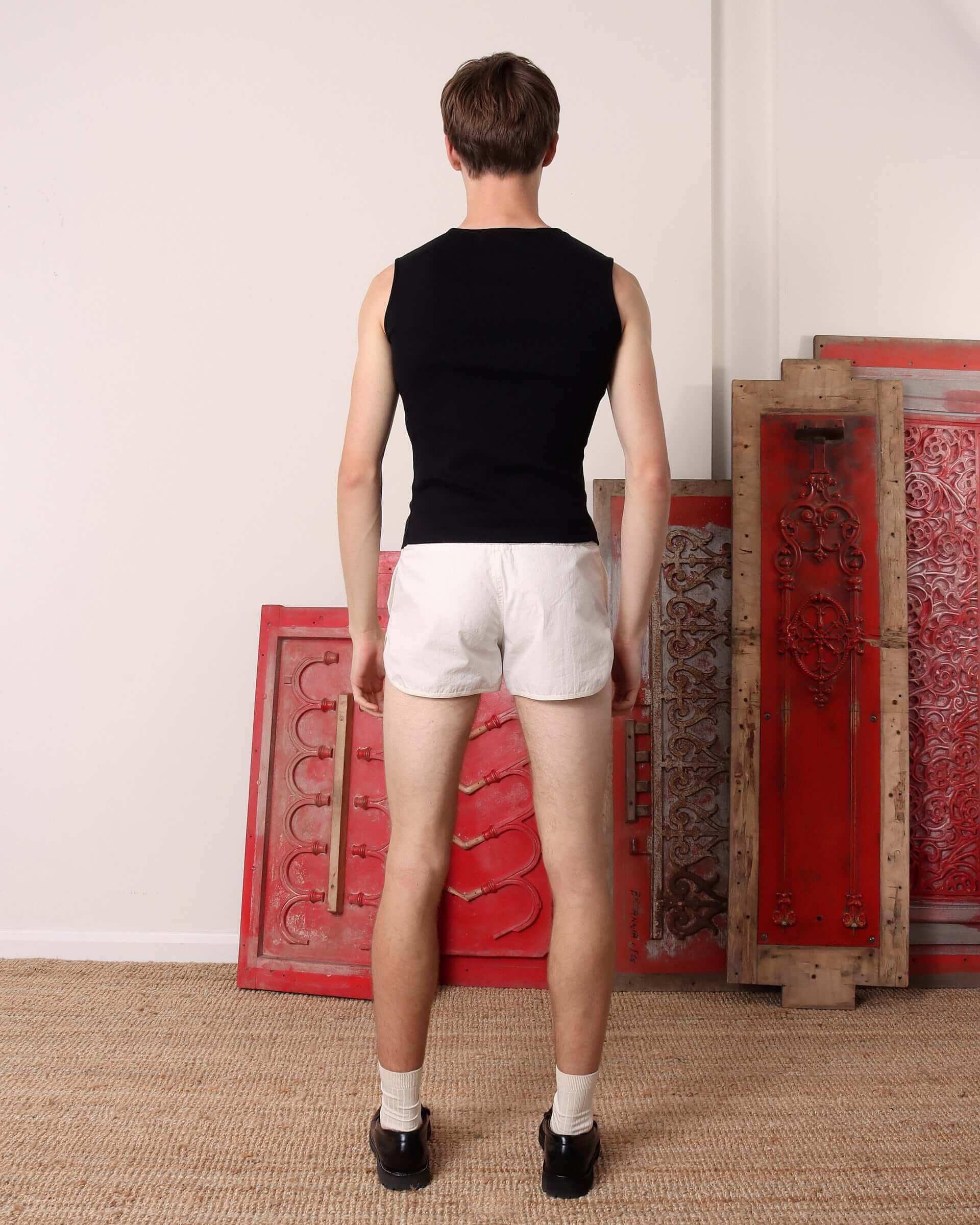 A model shows the back of the 'Cian' Buttoned Top in black.