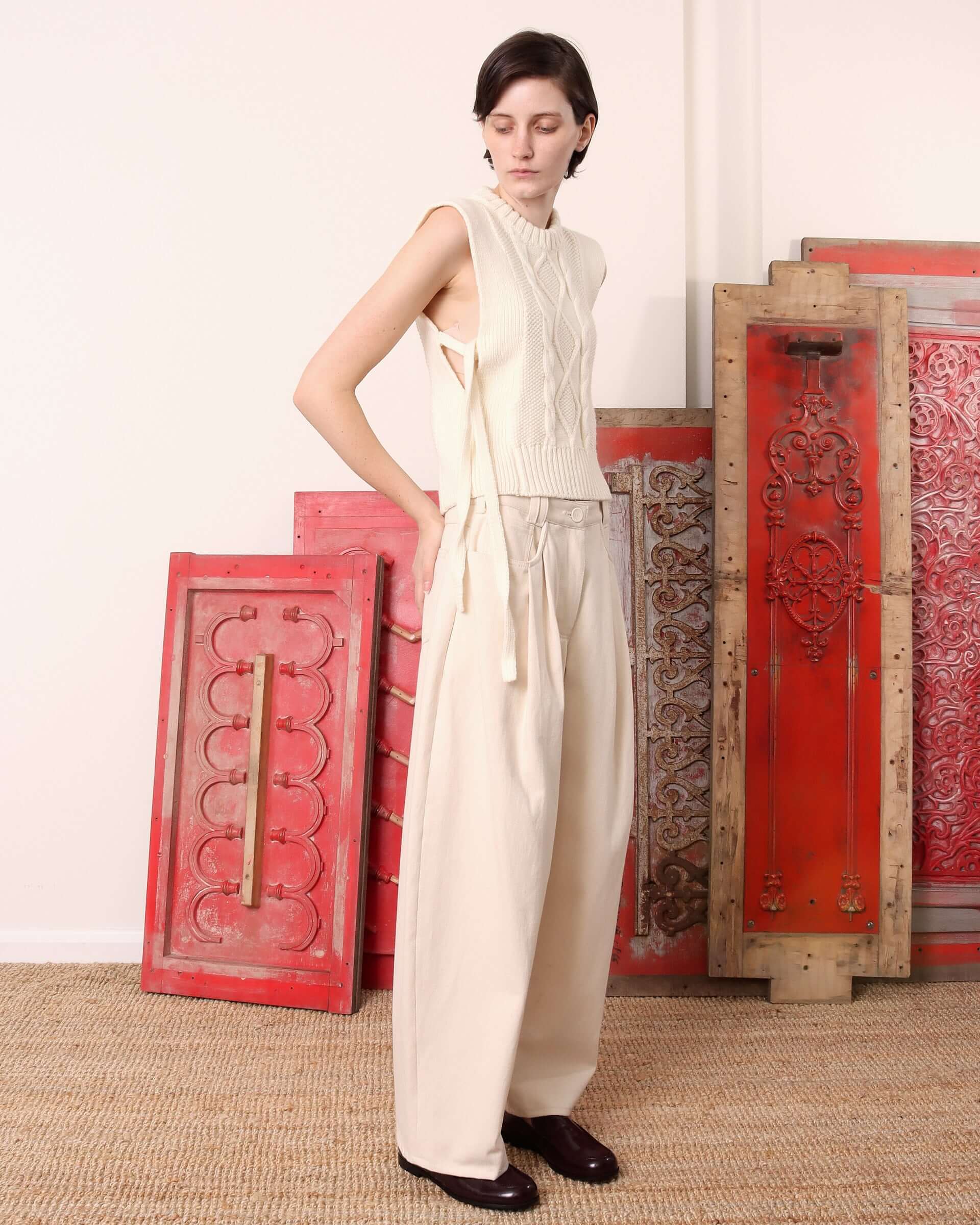 A model shows the side of the ecru 'Blandine' Vest, better showing the side-tie detail.