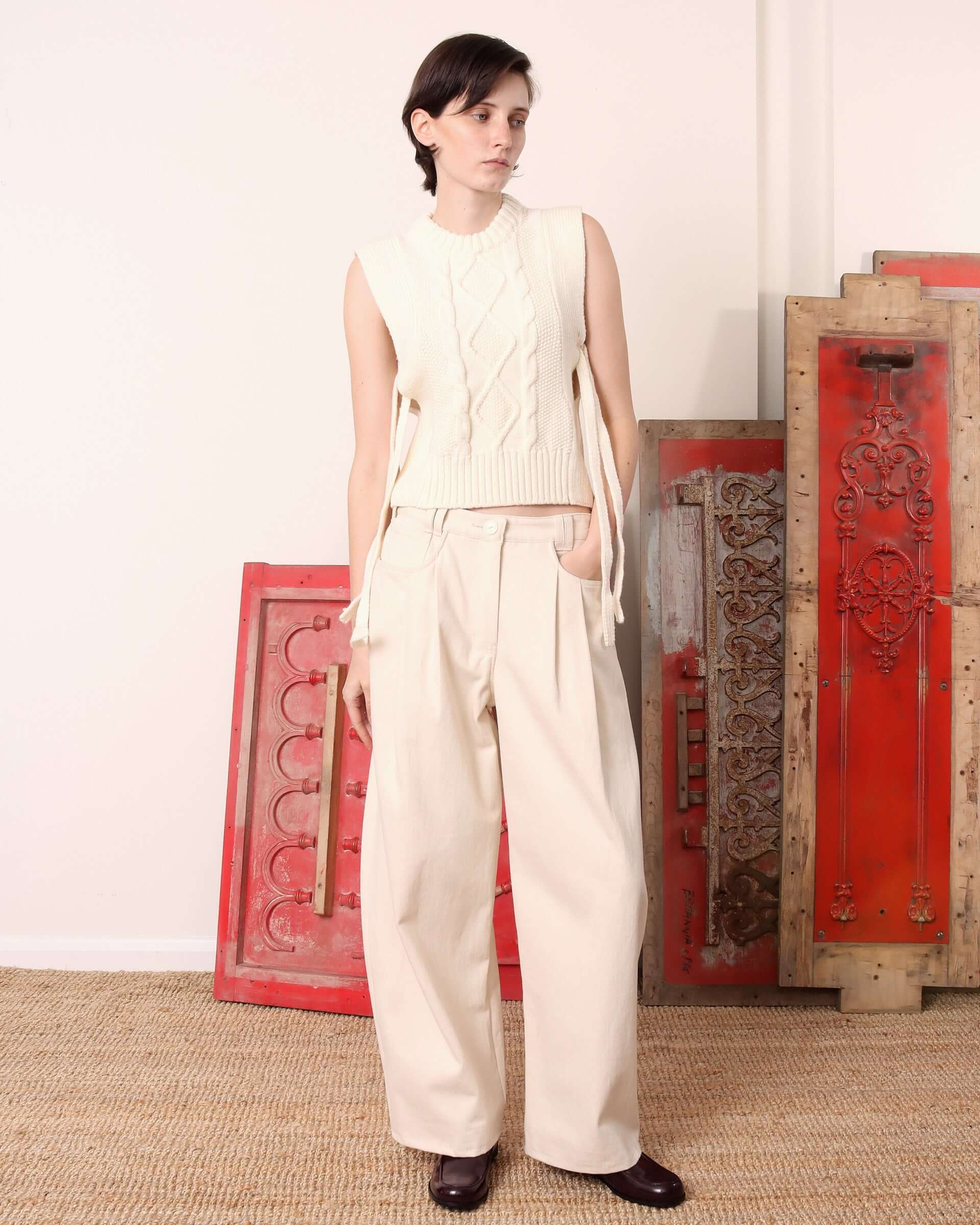 A model wears the 'Blandine' Vest in ecru with the tie sides untied, paired with matching ecru trousers.