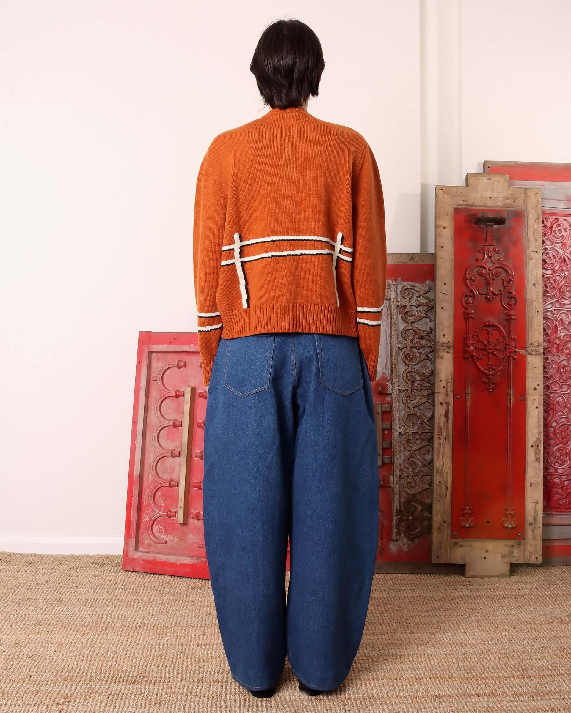 A model shows the back of the 'Cyril' Lamb Cardigan in tawny and the fence motif there.