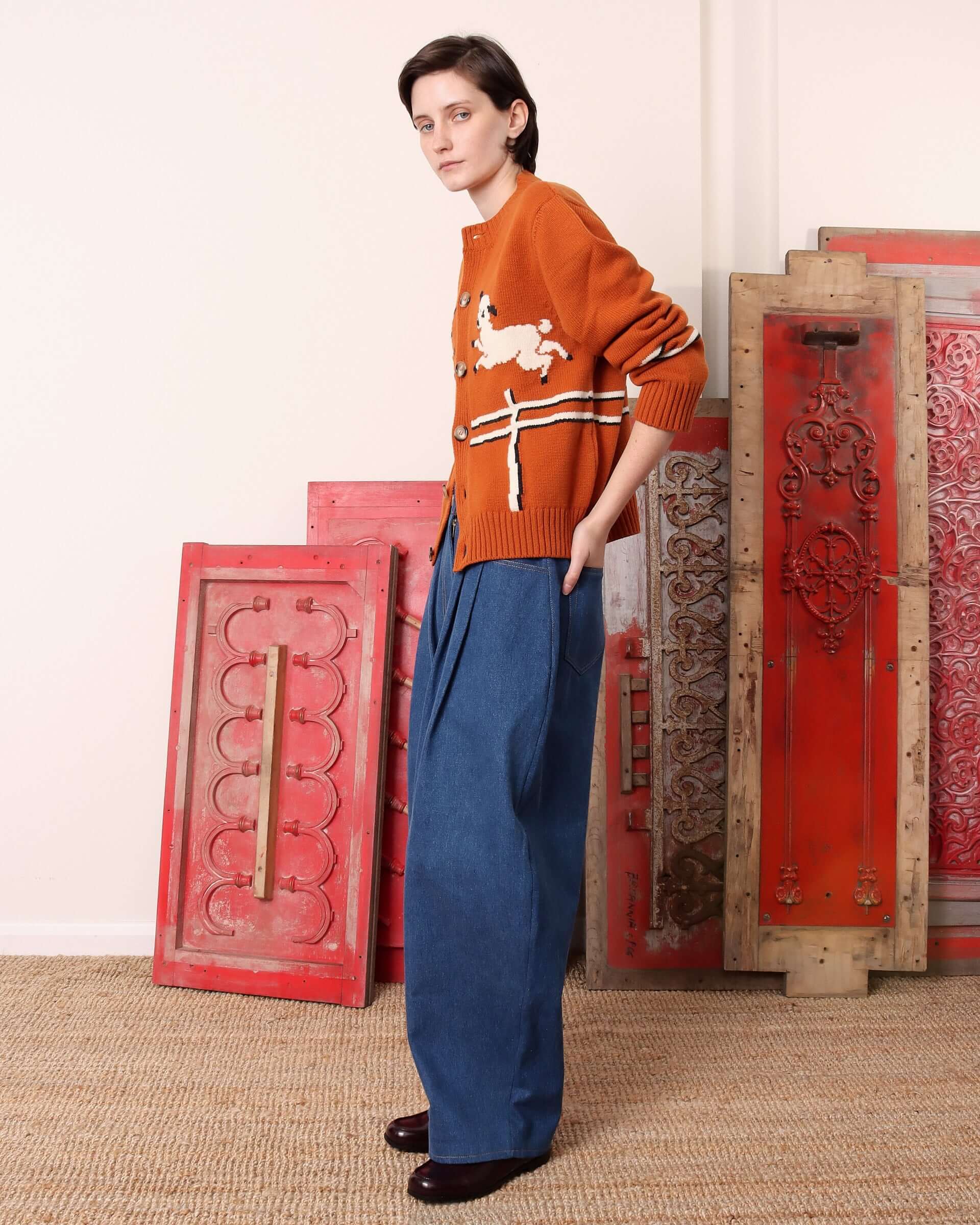 A model shows the side of the 'Cyril' Lamb  Motif Cardigan in Tawny.