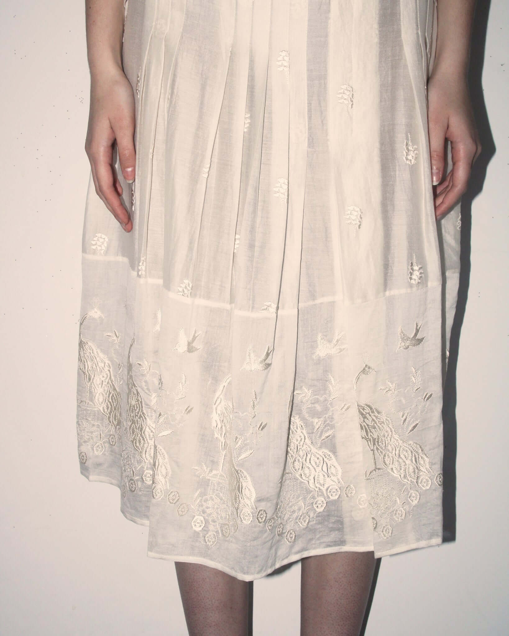 A detailed shot of the 'Ada' Skirt showing the semi-sheer cotton-silk fabric and delicate floral and bird motifs.