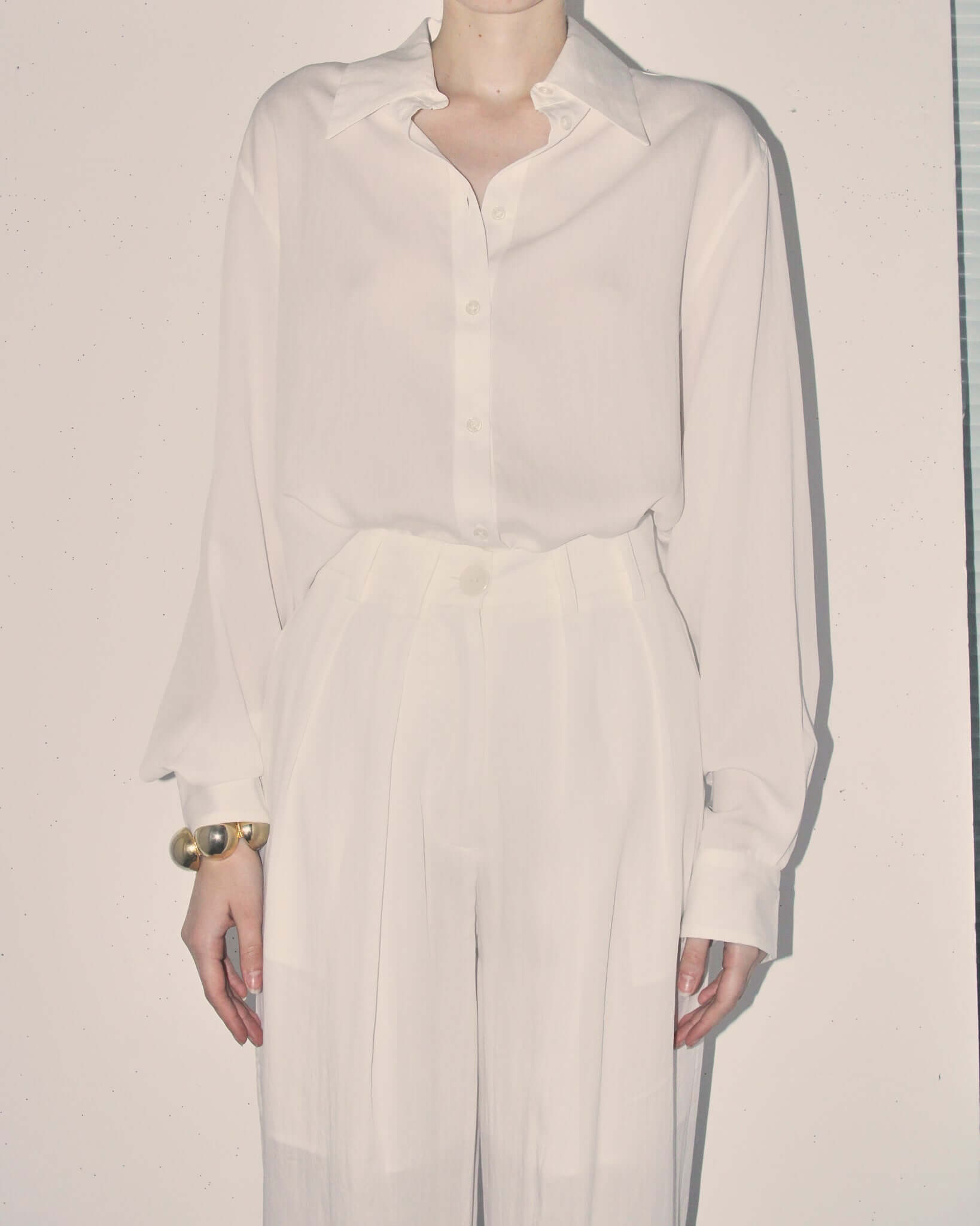 Detail shot of model wearing the 'Orla' Long Sleeve Shirt tucked into the matching 'Orla' pleated trousers as a set.