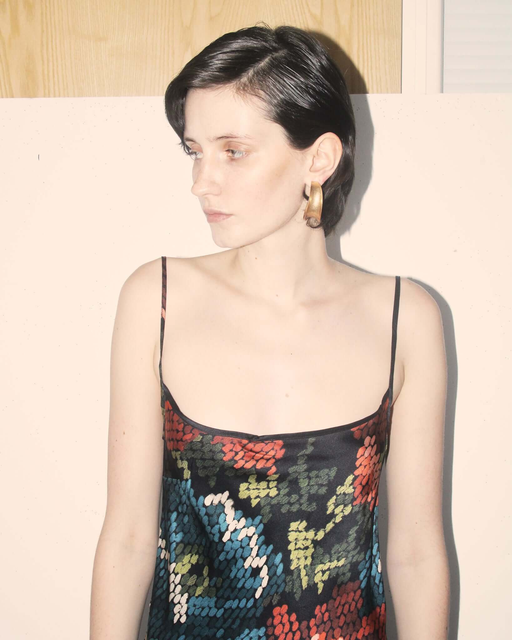 A detail shot of the a model showing the scoop neckline of the 'Willow' Slip Dress in black and floral.