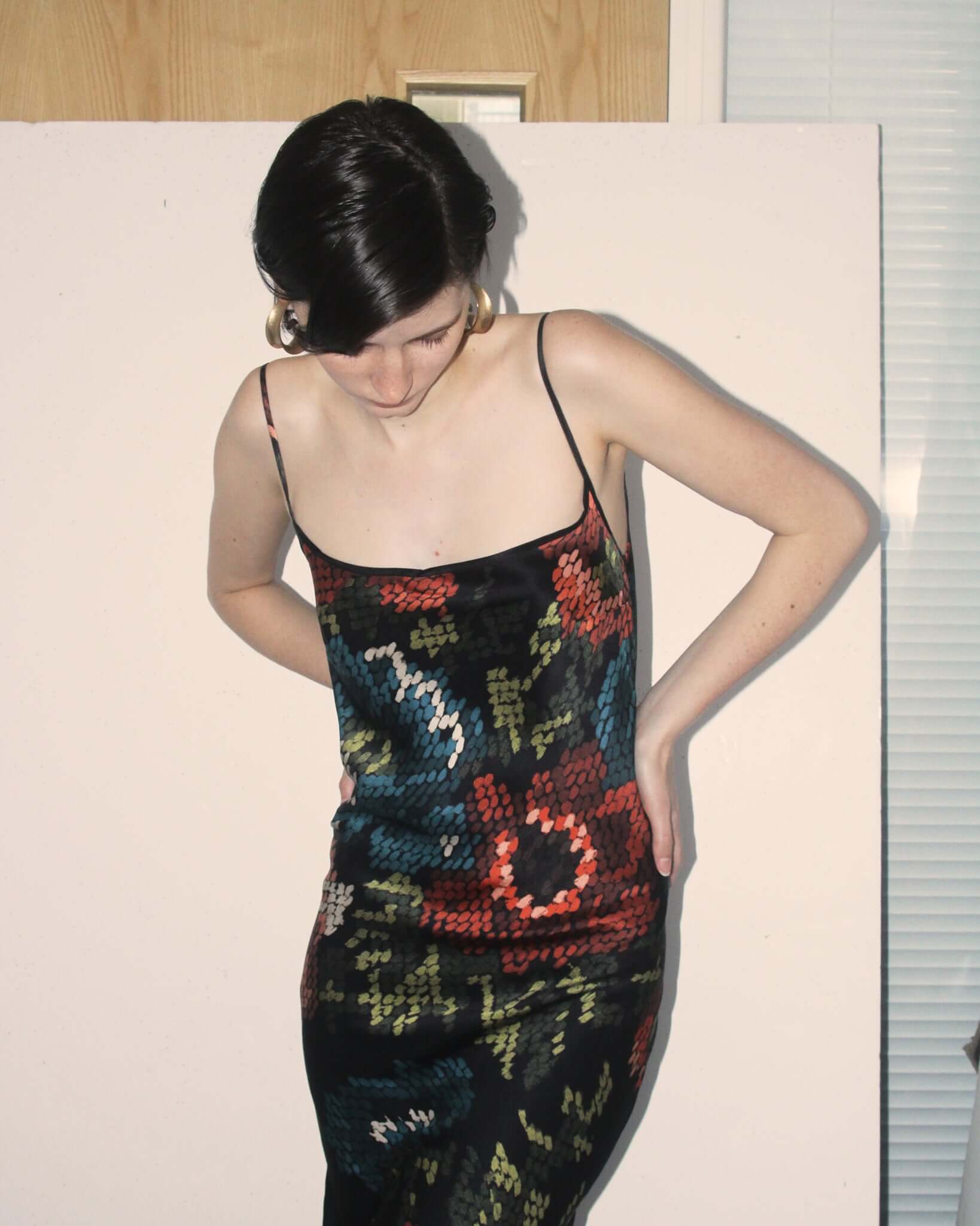 A detail shot of a model wearing the 'Willow' Slip Dress with brushwork-style floral print on a black silk background.