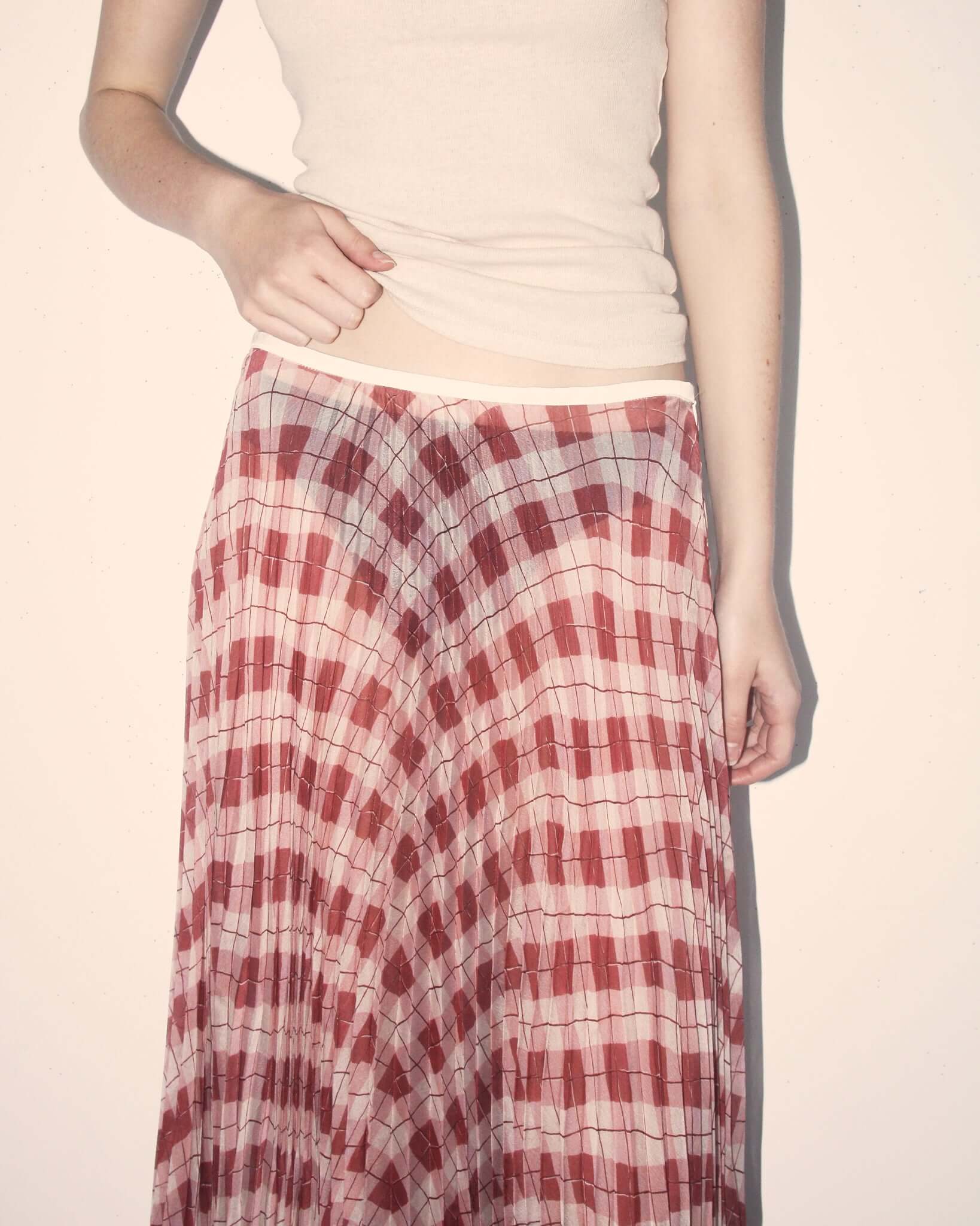A detail shot of a model wearing the pink and burgundy argyle 'Kate' Skirt, showing the  thin cream grosgrain bound waistband.