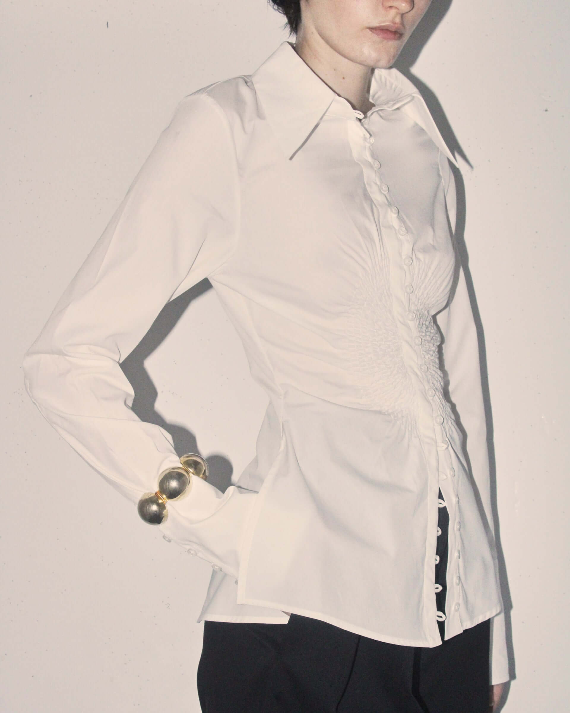 A detail shot of the 'Eva' Circle shirt in white showing its circular shaped ruching in the centre and many  buttons.
