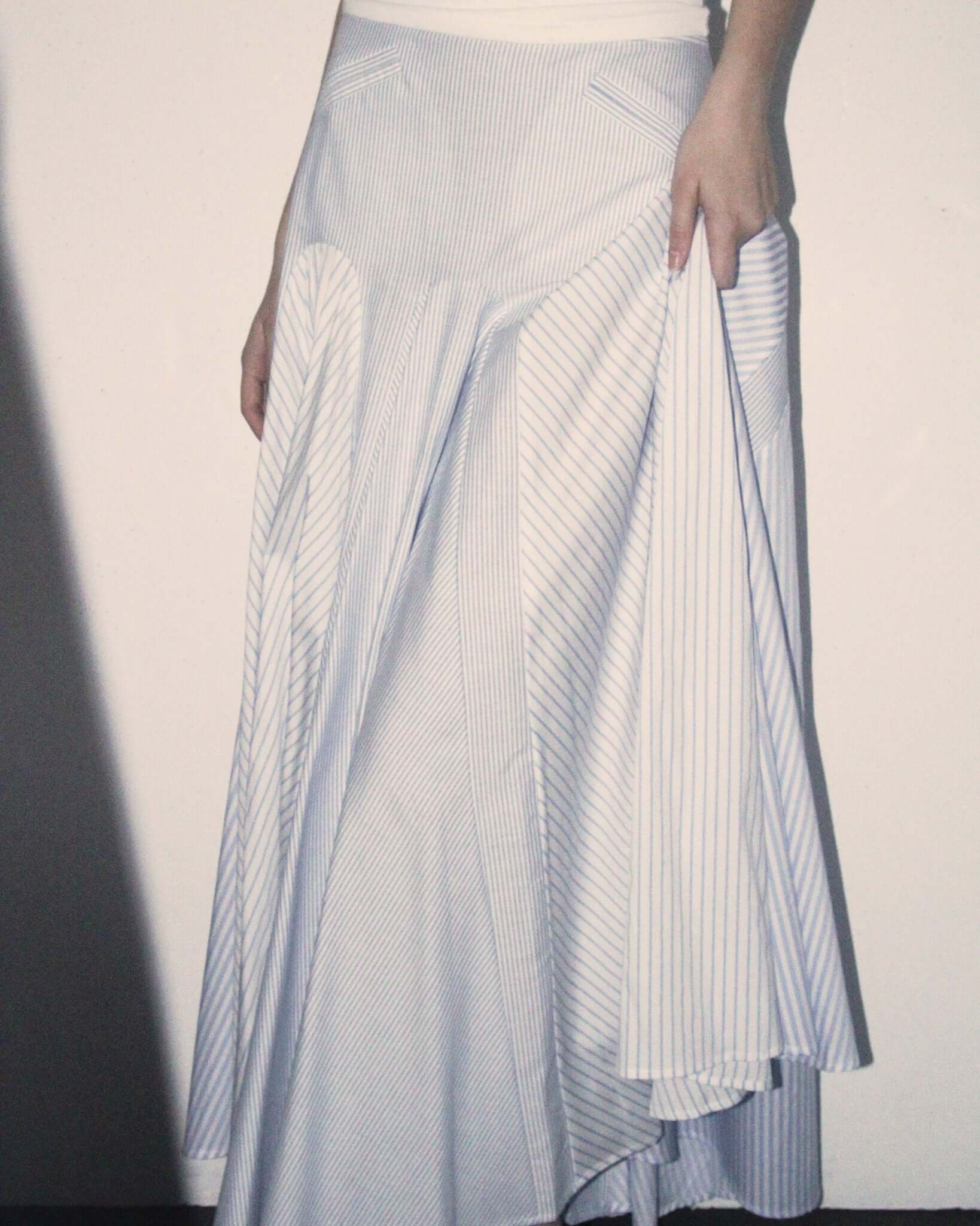 A detail shot of a model wearing the blue and white 'Taali' Skirt showing the different pleated sections.