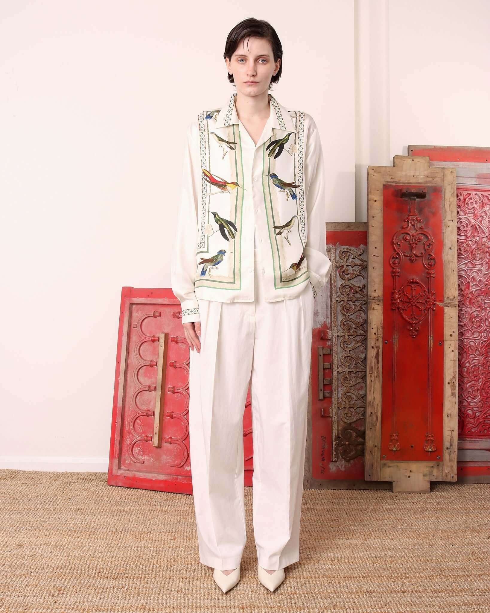 Model wearing the 'Birdwatcher' long sleeve shirt with matching white pleated trousers.