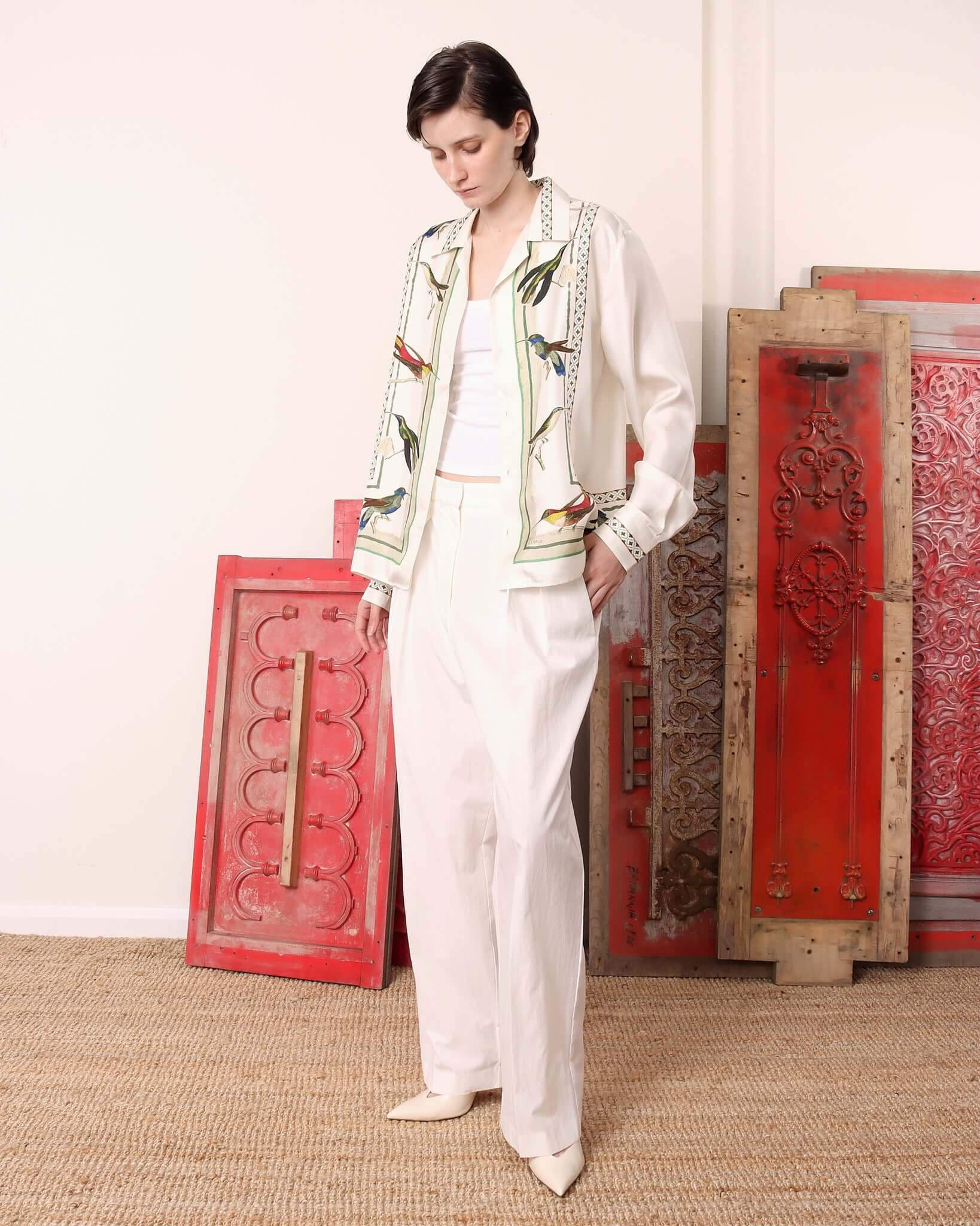 Model with one hand in her pocket, wearing the long sleeved silk 'Birdwatcher' shirt.