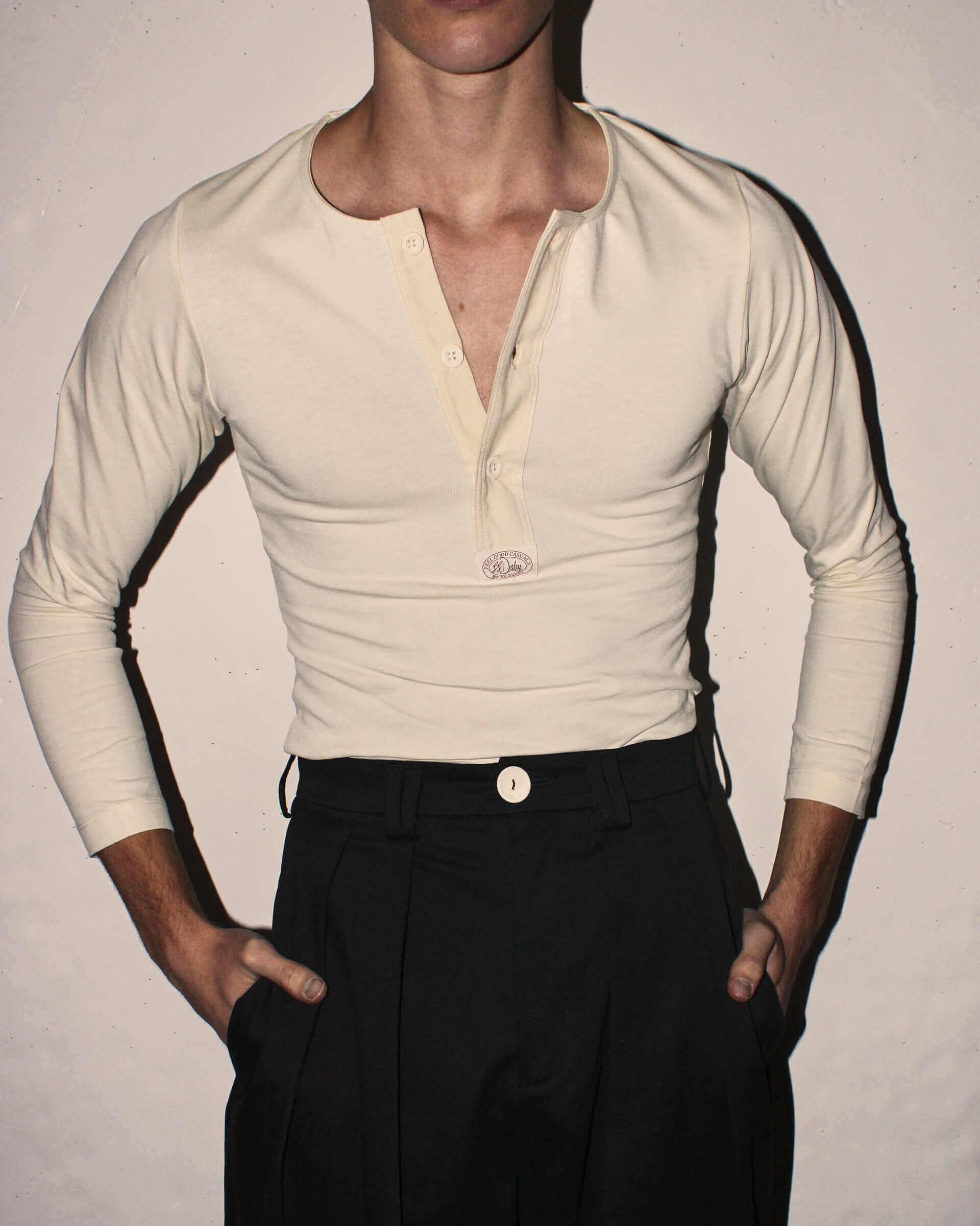 A detail shot of the 'Harold' Henley with long sleeves in ecru tucked into black 'George' Trousers. 