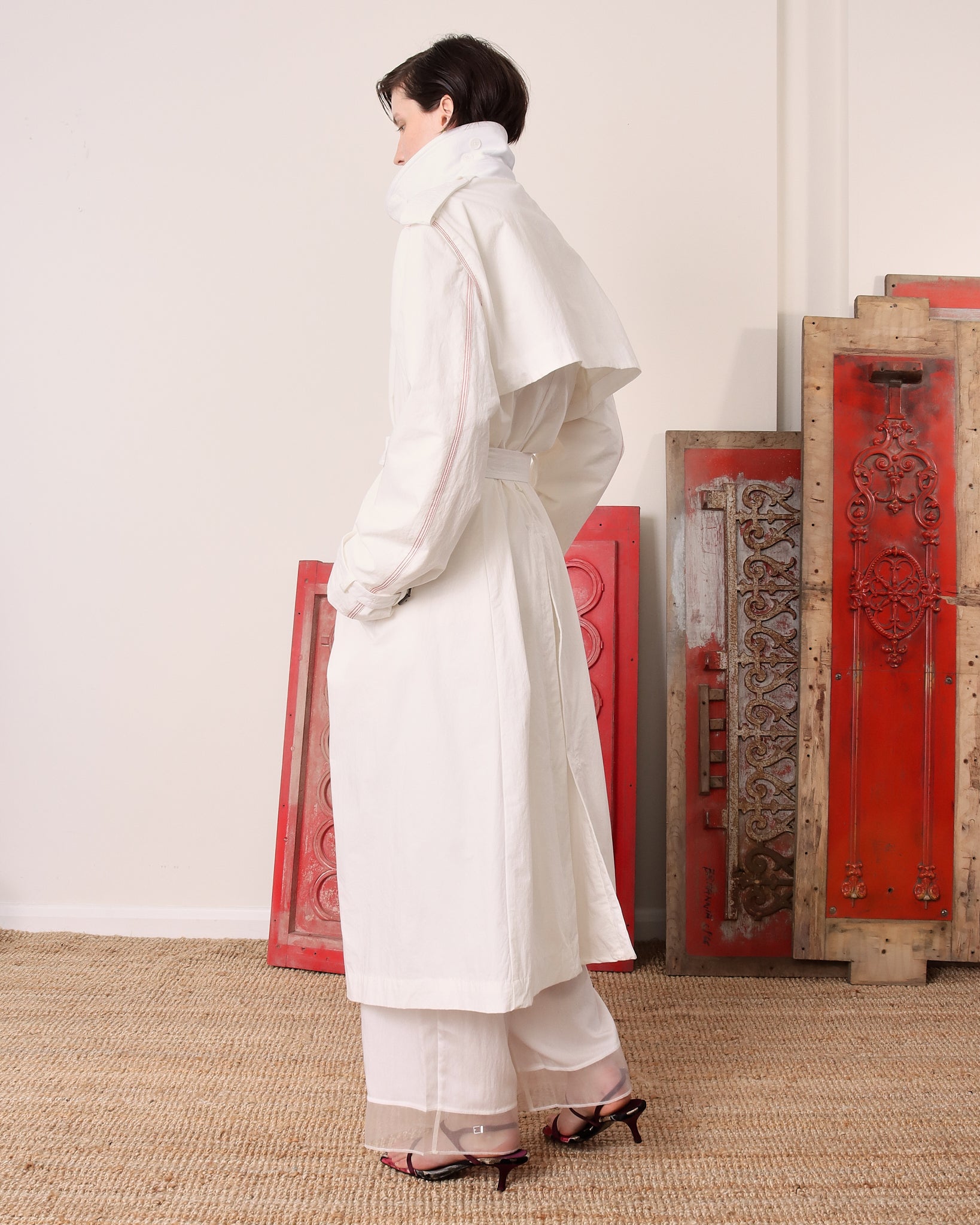 A model shows the back of the white 'Sophia trench and its flowing back panel and shoulder epaulettes.