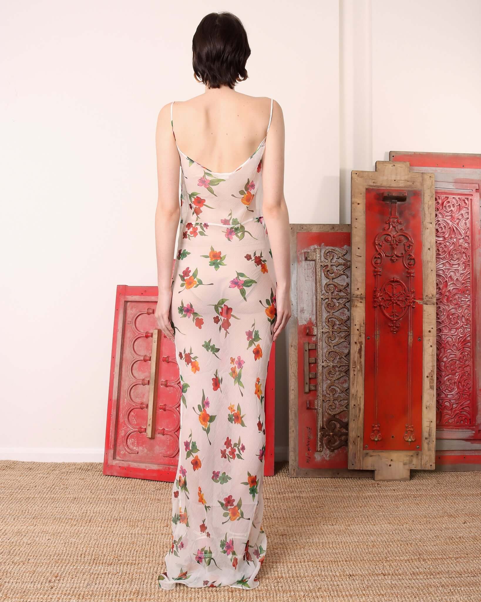 A model shows the low cut back of the 'Chelsea' Slip Dress in white and floral print.