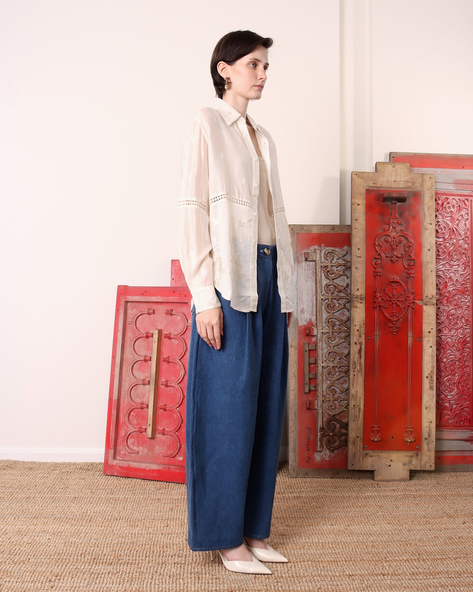 A model shows the side of the 'Ada' Long Sleeve Shirt in white paired with blue denim.
