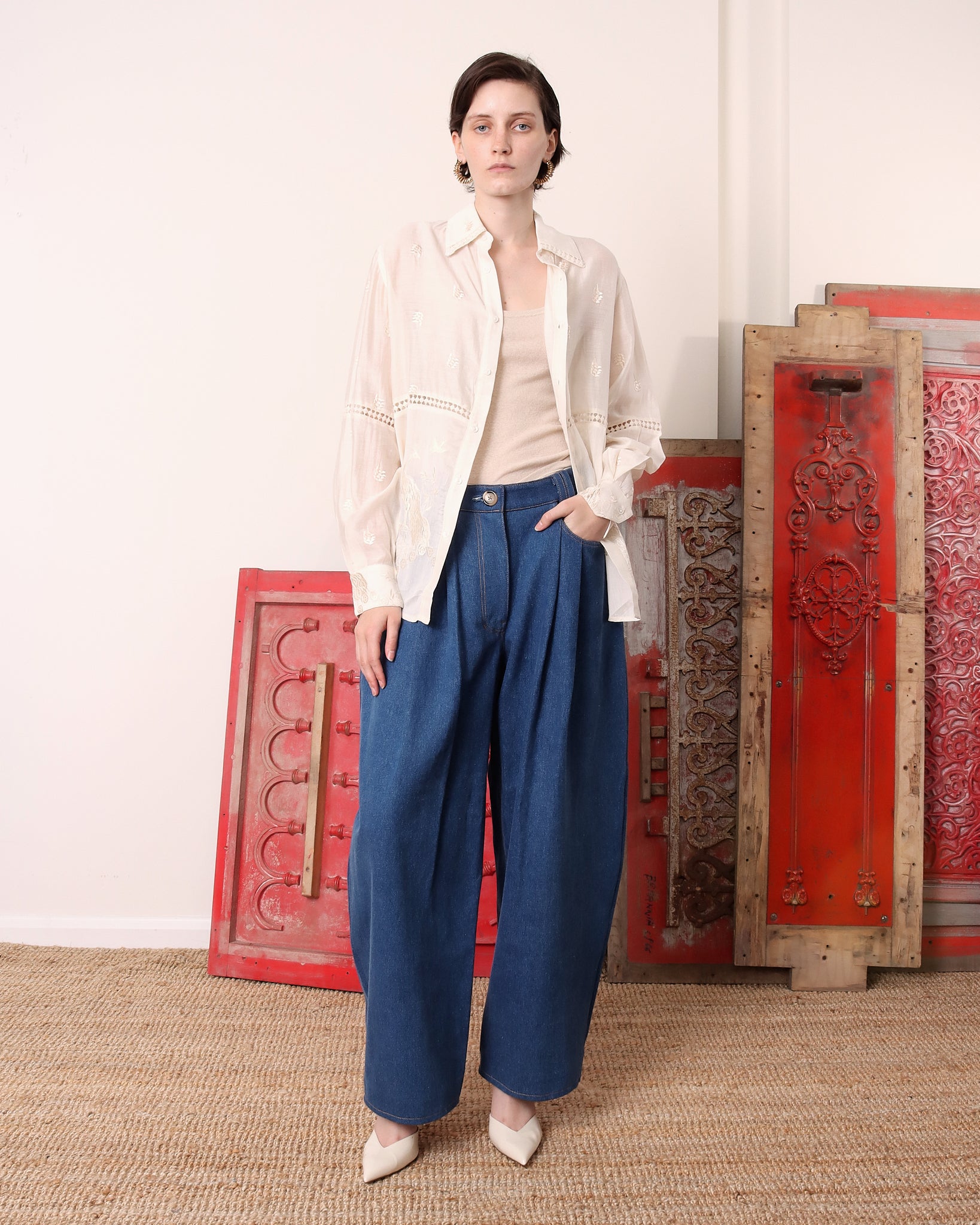 A model wears the 'Ada' Long Sleeve shirt and has her hand in the pocket of a pair of blue denim trousers.