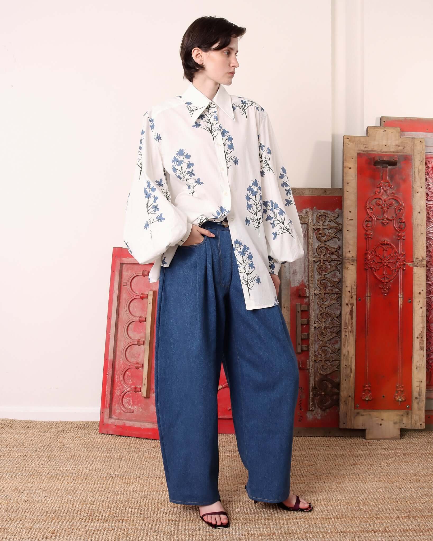 A model wears the printed 'Clem' Shirt half tucked into blue denim trousers.